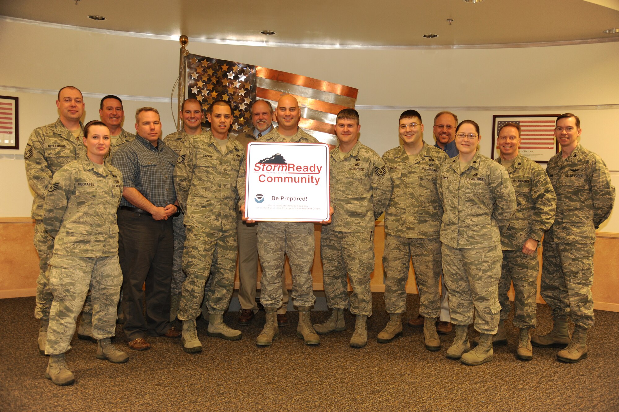 Two members of the National Weather Service (back row) stand amongst senior leadership members and Airmen from various agencies throughout the 319th Air Base Wing on Dec. 10, 2012, who helped Grand Forks Air Force Base, N.D., become certified as StormReady by the NWS. Tech. Sgt. Ben Hall, NCO in charge of operational readiness for the 319th ABW Inspector General’s Office, holds up a banner recognizing the installation’s accomplishment.  Storm Ready is a NWS program designed to help community leaders and emergency managers strengthen local safety and severe weather response programs through advanced planning, education and awareness.  (U.S. Air Force photo/Airman 1st Class Xavier Navarro)