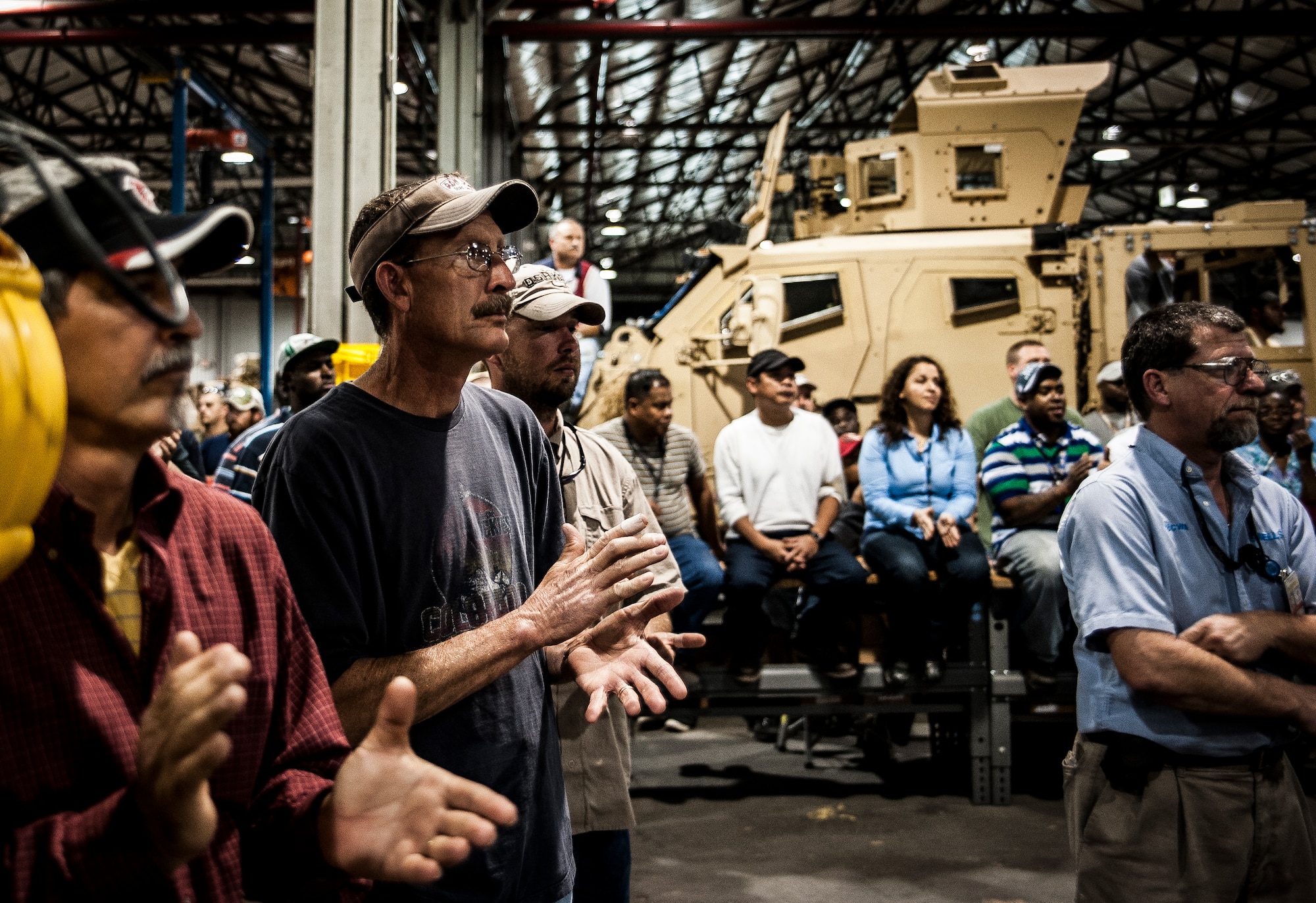 Attendees applaud after hearing a speech from Christopher Miller, Space and Naval Warfare Systems Center Atlantic executive director, at a ceremony held to commemorate the rapid acquisition, integration of electronics and delivery of more than 27,000 MRAP vehicles sent to Iraq and Afghanistan, Dec. 10, 2012, from the SPAWAR integration facility on Joint Base Charleston – Weapons Station, S.C. The team at SPAWAR initially integrated five vehicles a day, but when demand for the vehicles rose, the team stepped production up to integrating 50 vehicles a day. The team even reached the lofty goal of integrating 75 MRAPSs in one day. (U.S. Air Force photo/ Senior Airman Dennis Sloan)