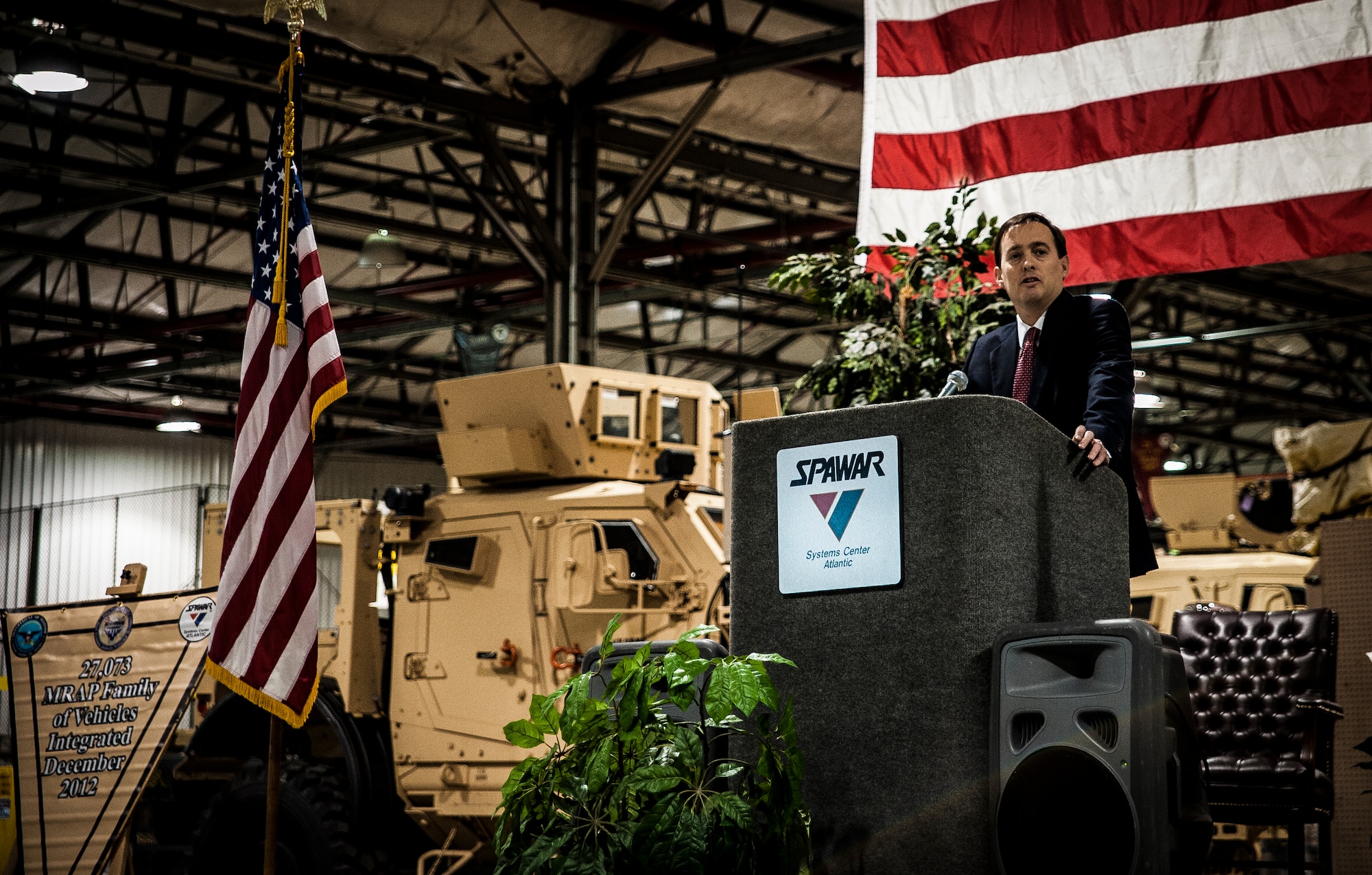 Christopher Miller, Space and Naval Warfare Systems Center Atlantic executive director, speaks to invited guests and workers who helped integrate the mine-resistant, ambush-protected vehicles at a ceremony held to commemorate the rapid acquisition, integration of electronics and delivery of more than 27,000 MRAP vehicles sent to Iraq and Afghanistan, Dec. 10, 2012, from the SPAWAR integration facility on Joint Base Charleston – Weapons Station, S.C. The team at SPAWAR initially integrated five vehicles a day, but when demand for the vehicles rose, the team stepped production up to integrating 50 vehicles a day. The team even reached the lofty goal of integrating 75 MRAPSs in one day. (U.S. Air Force photo/ Senior Airman Dennis Sloan)