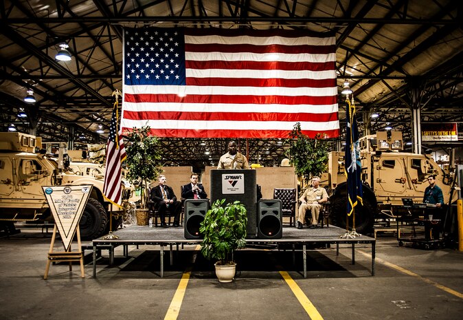 Navy Capt. Mark Glover, Space and Naval Warfare Systems Center Atlantic commanding officer, welcomes attendees to a ceremony held to commemorate the rapid acquisition, integration of electronics and delivery of more than 27,000 MRAP vehicles sent to Iraq and Afghanistan, Dec. 10, 2012, from the  SPAWAR integration facility on Joint Base Charleston – Weapons Station, S.C. The team at SPAWAR initially integrated five vehicles a day, but when demand for the vehicles rose, the team stepped production up to integrating 50 vehicles a day. The team even reached the lofty goal of integrating 75 MRAPSs in one day. (U.S. Air Force photo/ Senior Airman Dennis Sloan)