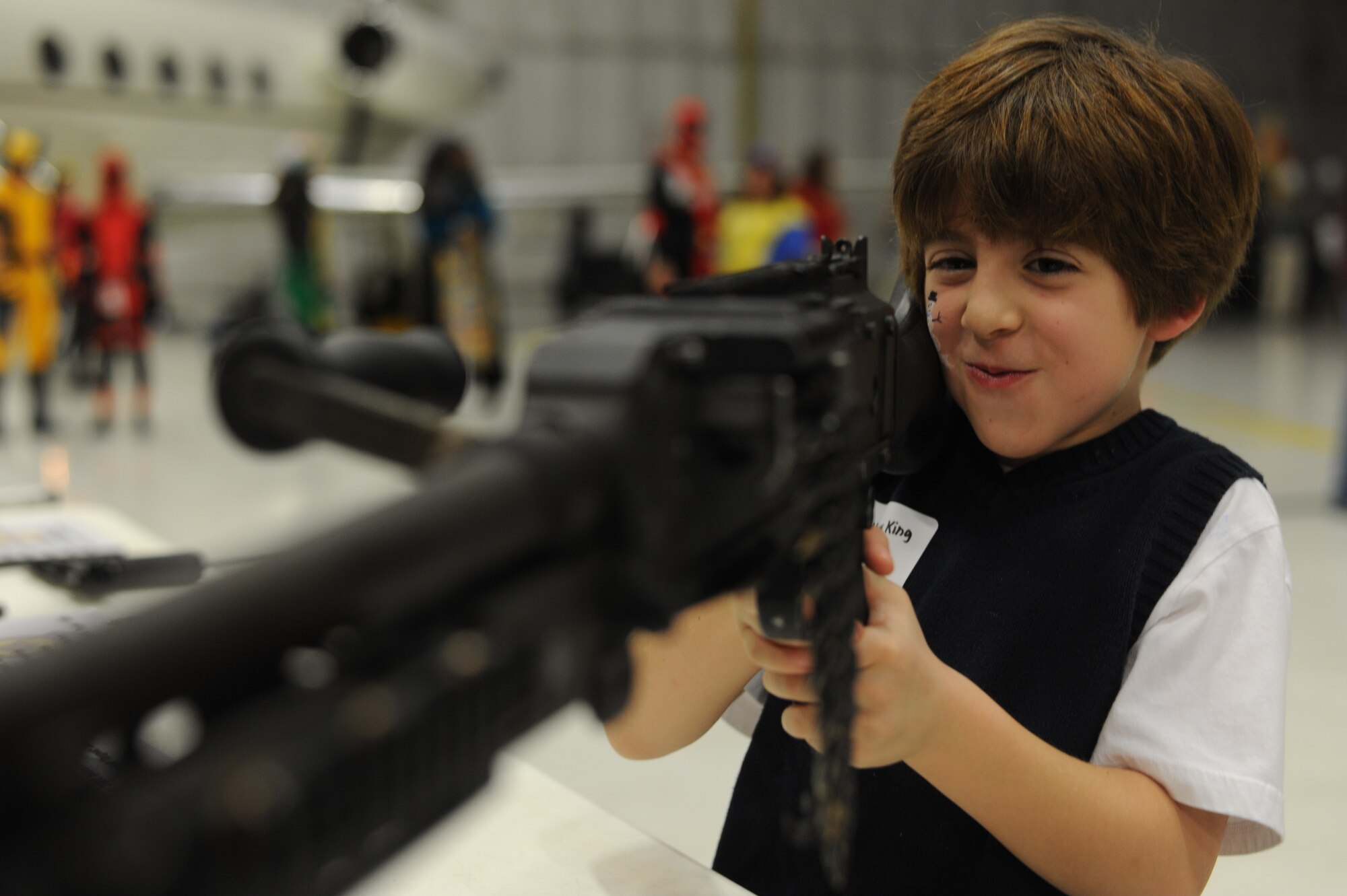 Matthew King, 7, son of Asusena King, holds a M240B machine gun at the Combat Arms Training Maintenance booth during the 25th Annual Parents and Children Fighting Cancer Christmas Party, Dec. 8, 2012 in Hangar 3 on Joint Base Andrews, Md. This year was the King family’s first time attending the annual PCFC event. (U.S. Air Force photo/Senior Airman Bahja Jones) 