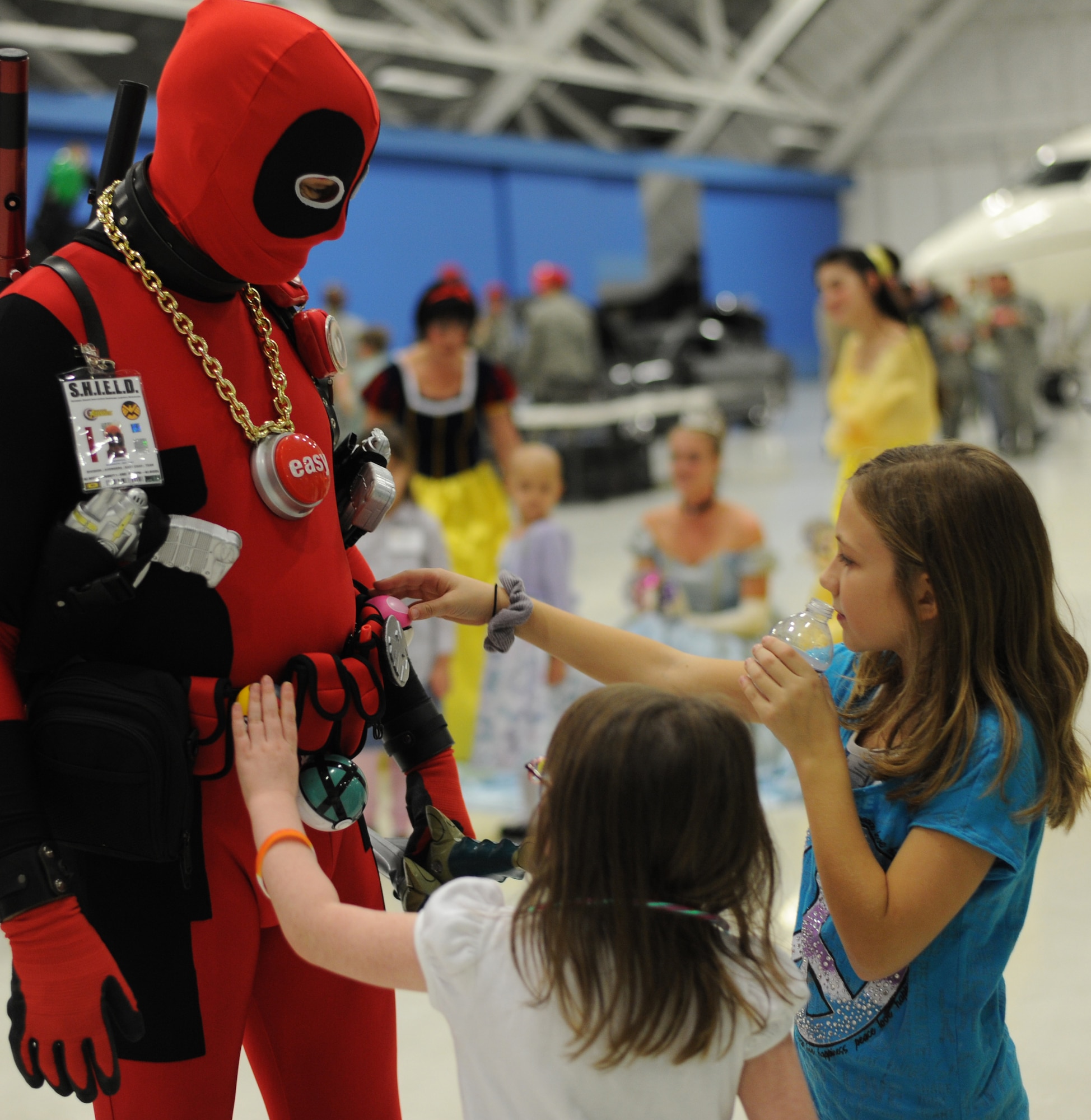 Alexis, 7, daughter of Ruby Markley, and Kaitlyn, 9, daughter of Stormy Knowles a PCFC volunteer, admire the gadgets on the Marvel character Dead Pool’s costume at the 25th Annual Parents and Children Fighting Cancer Christmas Party, Dec. 8, 2012 in Hangar 3 on Joint Base Andrews, Md. The East Coast Avengers group volunteered during the event dressed as well known characters from the X-Men. (U.S. Air Force photo/Senior Airman Bahja J. Jones)