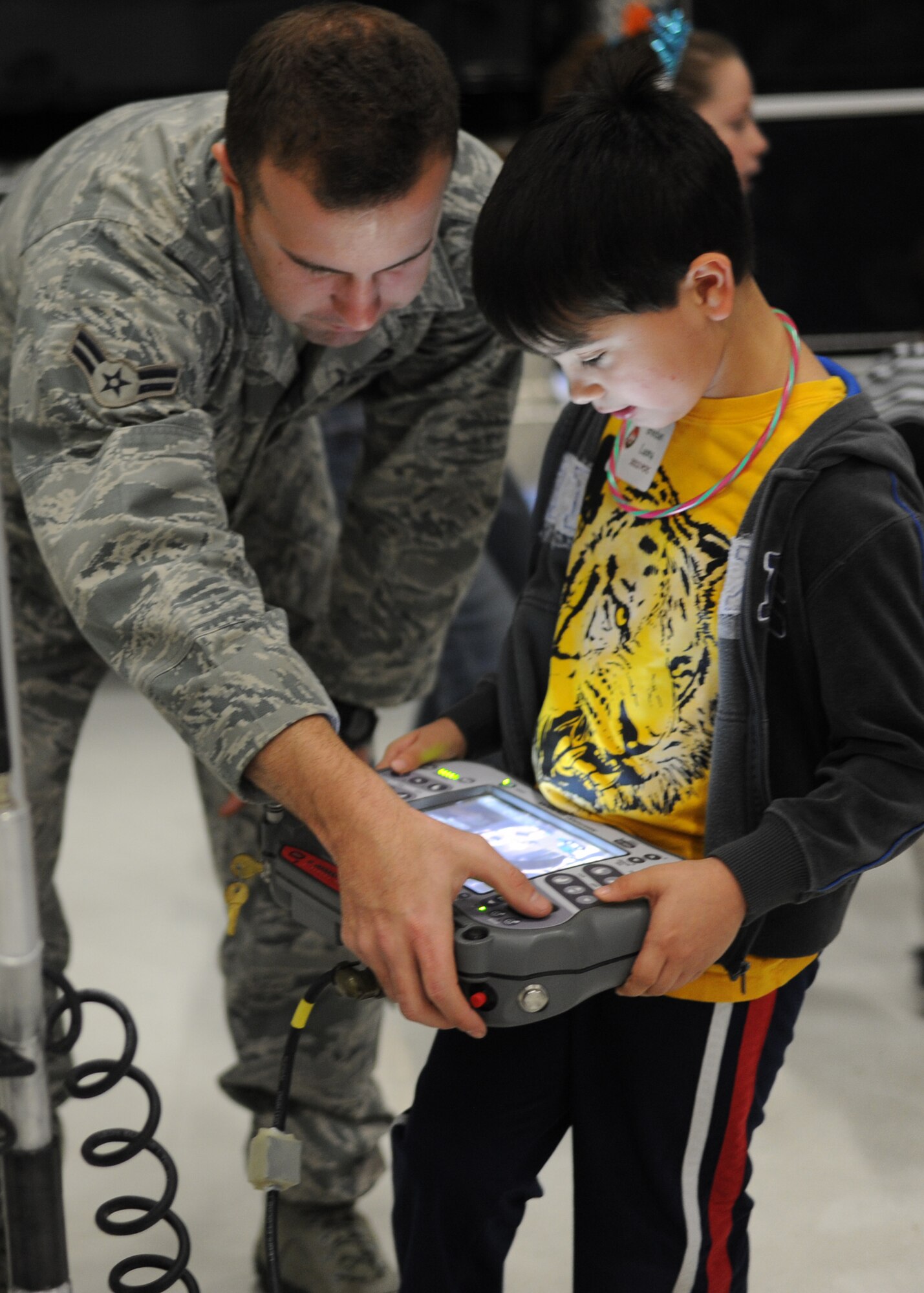 Airman 1st Class Brian Barry, 11th Civil Engineer Squadron explosive ordinance disposal journeyman, shows Brendon, 7, son of Retired Col. Mary Purdue, how to use the controller on the F6 EOD robot during the 25th Annual Parents and Children Fighting Cancer Christmas Party, Dec. 8, 2012 in Hangar 3 on Joint Base Andrews, Md. The annual PCFC event allows military families whose lives have been affected by cancer to come together and enjoy a free holiday celebration with food, performances, displays and special visit from Mr. and Mrs. Santa Claus. (U.S. Air Force photo/Senior Airman Bahja J. Jones) 