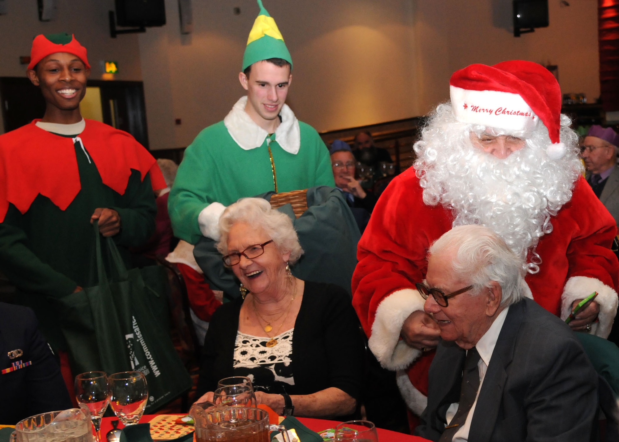 Santa Claus and his elves hand out candy during the Senior Citizens Christmas party Dec. 12, 2012, at RAF Mildenhall, England. The Christmas party included lunch with service members, a raffle, bingo and a visit from Santa Claus. (U.S. Air Force photo by Airman 1st Class Kelsey Waters/Released)