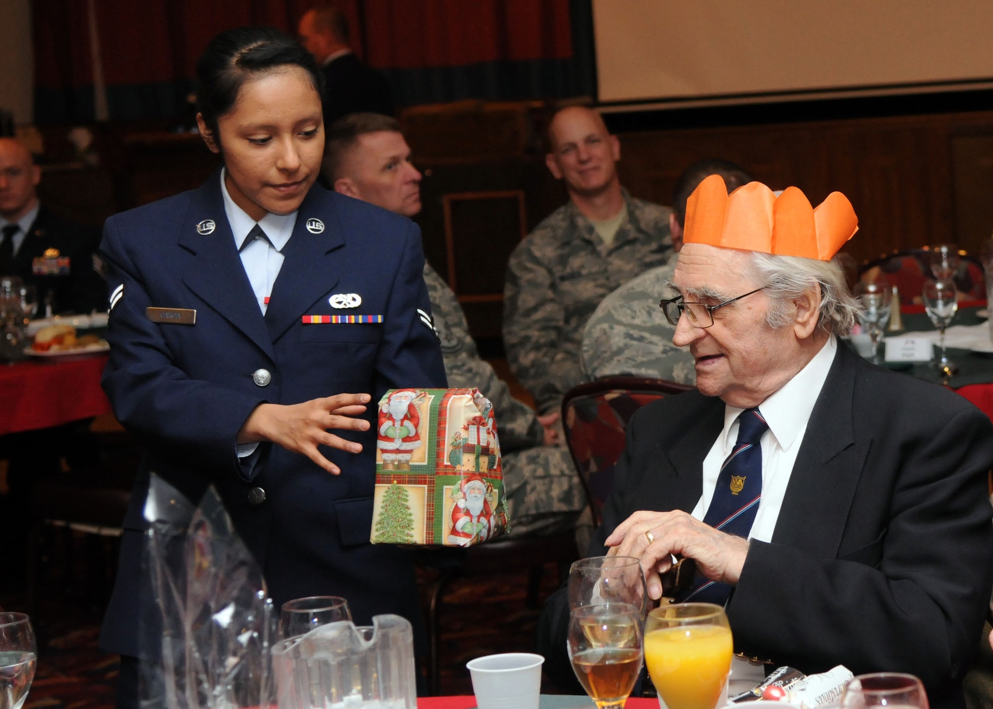 Airman 1st Class Sinai Garcia, 352nd Special Operations Maintenance Squadron communications navigations apprentice from Brownsville, Texas, gives a raffle prize to Eugne Hiluk, from Mildenhall, at the Senior Citizens Christmas party Dec. 12, 2012, at RAF Mildenhall, England. This year marked the 31st anniversary of the Senior Citizens Christmas party on RAF Mildenhall. (U.S. Air Force photo by Airman 1st Class Kelsey Waters/ Released)