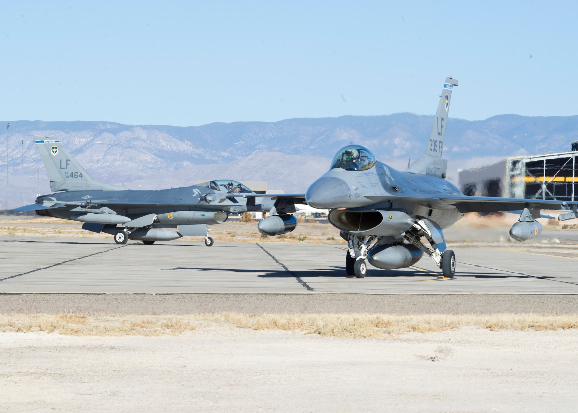 Two F-16 Fighting Falcons from the 309th Fighter Squadron, 56th Fighter Wing, Luke Air Force Base, Ariz., taxi to a hangar at Holloman Air Force Base, N.M., Dec. 7. The 309 FS deployed 18 F-16s and 190 supporting personnel to Holloman AFB to test infrastructure, range, and airspace capabilities to support the F-16 formal training unit, which will be moving to Holloman AFB. While here, the F-16s will fly 24 sorties per day. (U.S. Air Force photo by Senior Airman DeAndre Curtiss / Released) 
