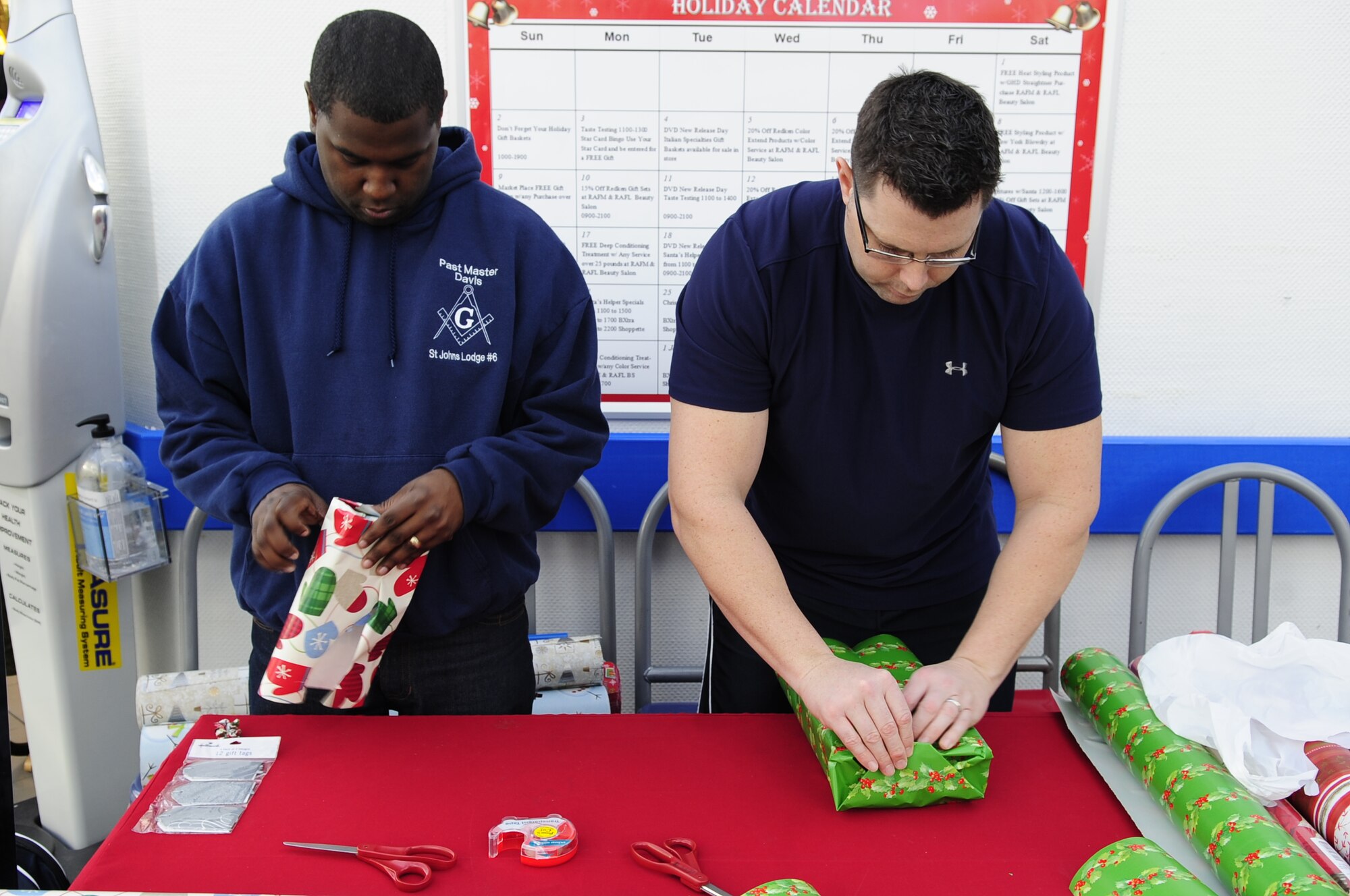 Staff Sgt. Michael Davis, 100th Maintenance Operations Squadron NCO in charge of scheduling maintenance training, and Master Sgt. Greg Gifford, 100th Maintenance Operations Squadron maintenance training superintendent, both from Chicago, wrap presents Dec. 11, 2012 at the B-Xtra on RAF Mildenhall, England. Every year, volunteers from around Team Mildenhall offer gift wrapping assistance to customers at the B-Xtra during the holiday season. (U.S. Air Force photo by Airman 1st Class Dillon Johnston/Released)