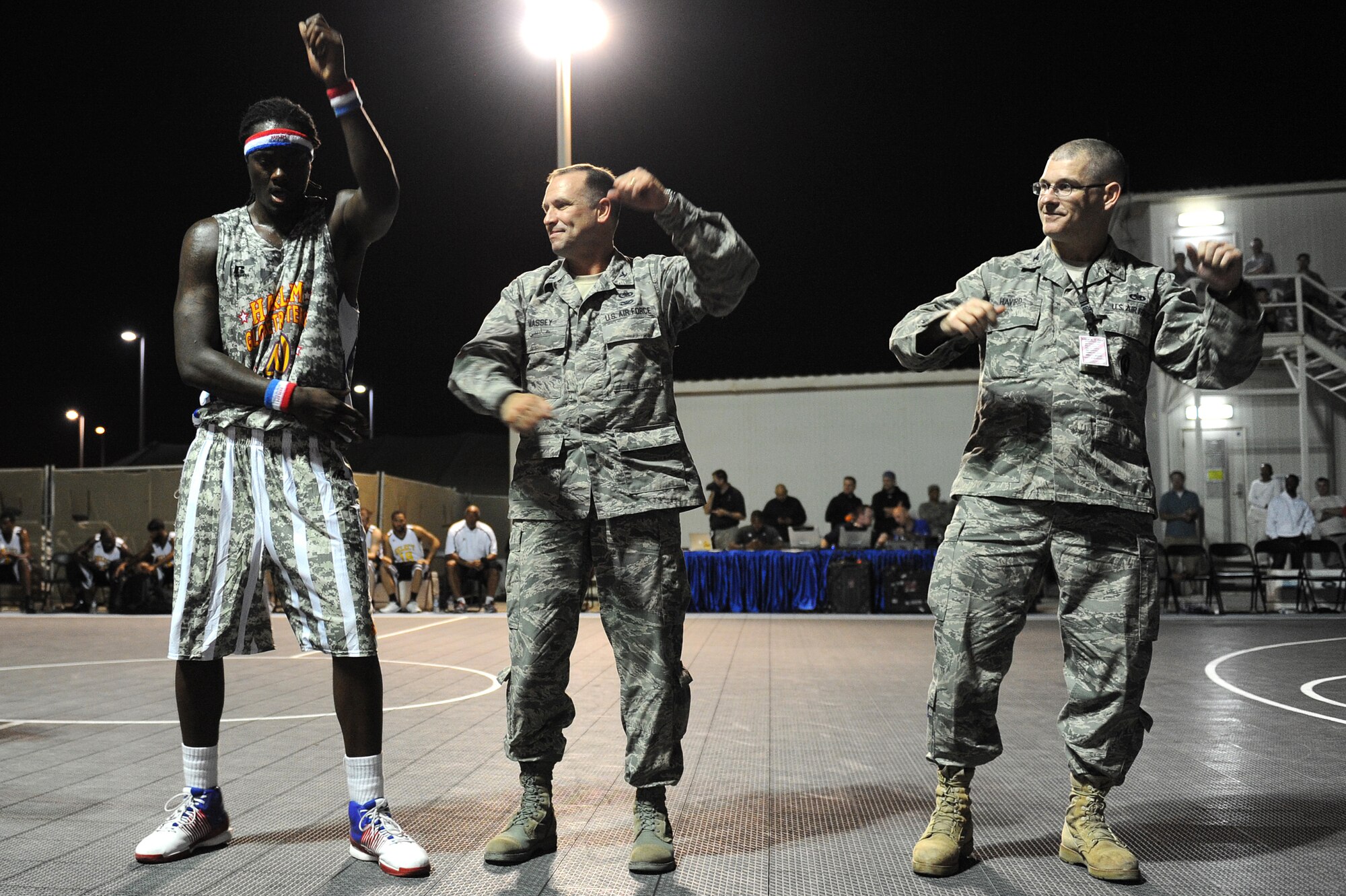 SOUTHWEST ASIA -- Harlem Globetrotter "Slick" Willie Shaw, Col. Max Massey, 380th Mission Support Group commander, and Col. Lawrence Havird, 380th Maintenance Group commander, perform "YMCA" during a performance at the 380th Air Expeditionary Wing Dec. 10, 2012. The Globetrotters  paid tribute to the troops by debuting camouflage uniforms during this 11th Holiday Military Tour. (U.S. Air Force photo/Tech. Sgt. Christina M. Styer) (RELEASED)