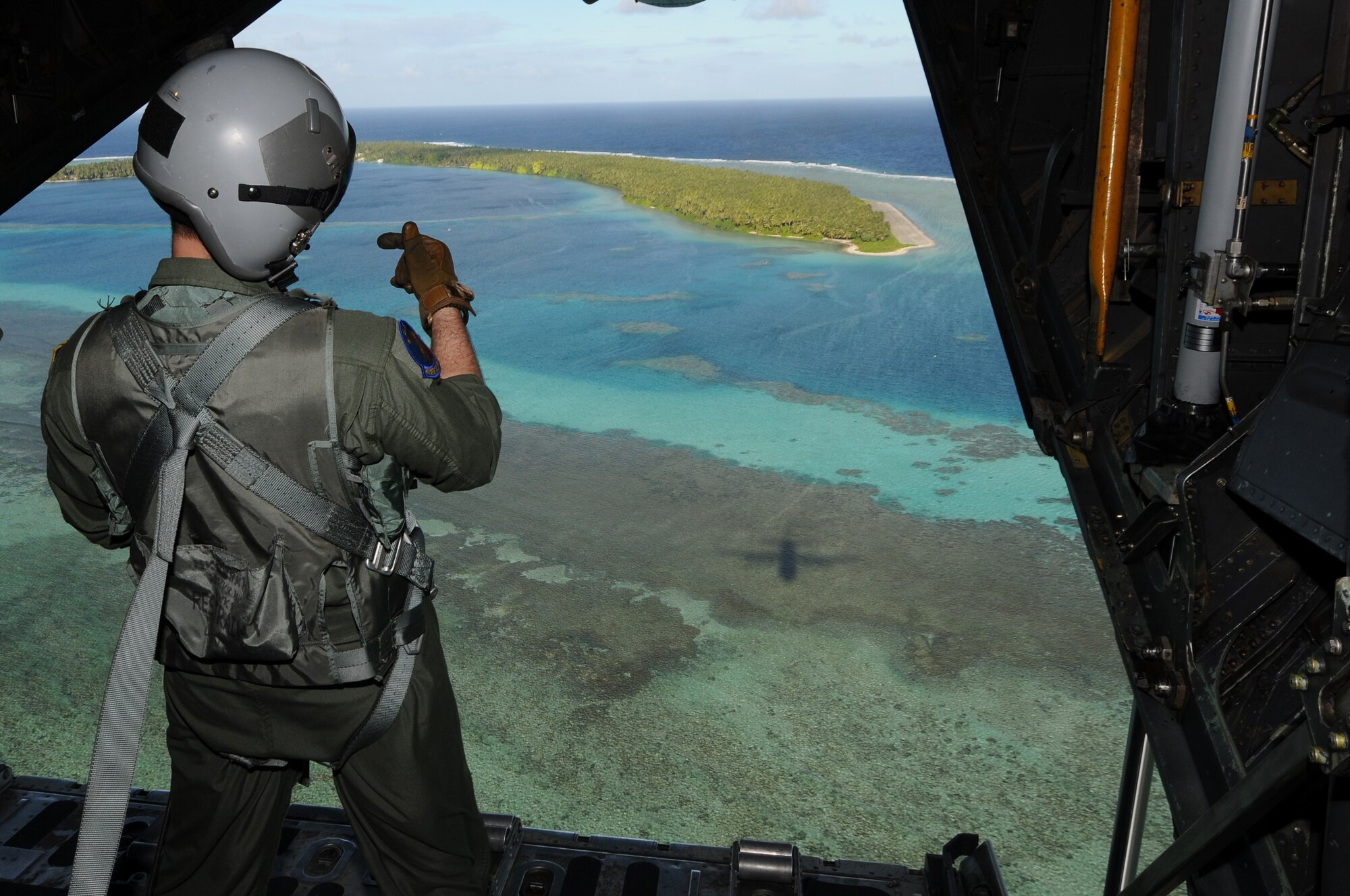 Senior Airman Benjamin Shest, an instructor loadmaster from the 36th Airlift Squadron at Yokota Air Base, Japan, provides coordinates via radio to the C-130 aircraft commander for proper alignment over Mokil Island prior to delivering humanitarian aid bundles as part of Operation Christmas Drop, Dec. 12, 2012. Each year OCD provides aid to more than 30,000 islanders in Chuuk, Palau, Yap, Marshall Islands and Commonwealth of the Northern Mariana Islands. This year is the 61st anniversary of OCD, making it the longest running humanitarian mission in the world. In total, there are eight planned days of air drops, with 54 islands scheduled to receive humanitarian aid.  (U.S. Air Force photo by Senior Airman Carlin Leslie/Released)