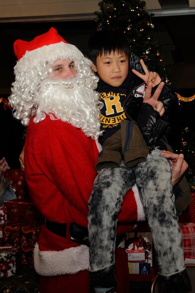 Airman 1st Class Troy Breckhelmer, 8th Logistics Readiness Squadron posses with a child from Illmagwon Orphanage during a Christmas party at the Loring Club on Kunsan Air Base, Republic of Korea, Dec 1, 2012. Breckhelmer spent the day as Santa for the children and assisted with delivering presents to them. (U.S. Air Force photo by Marcus Morris/released)