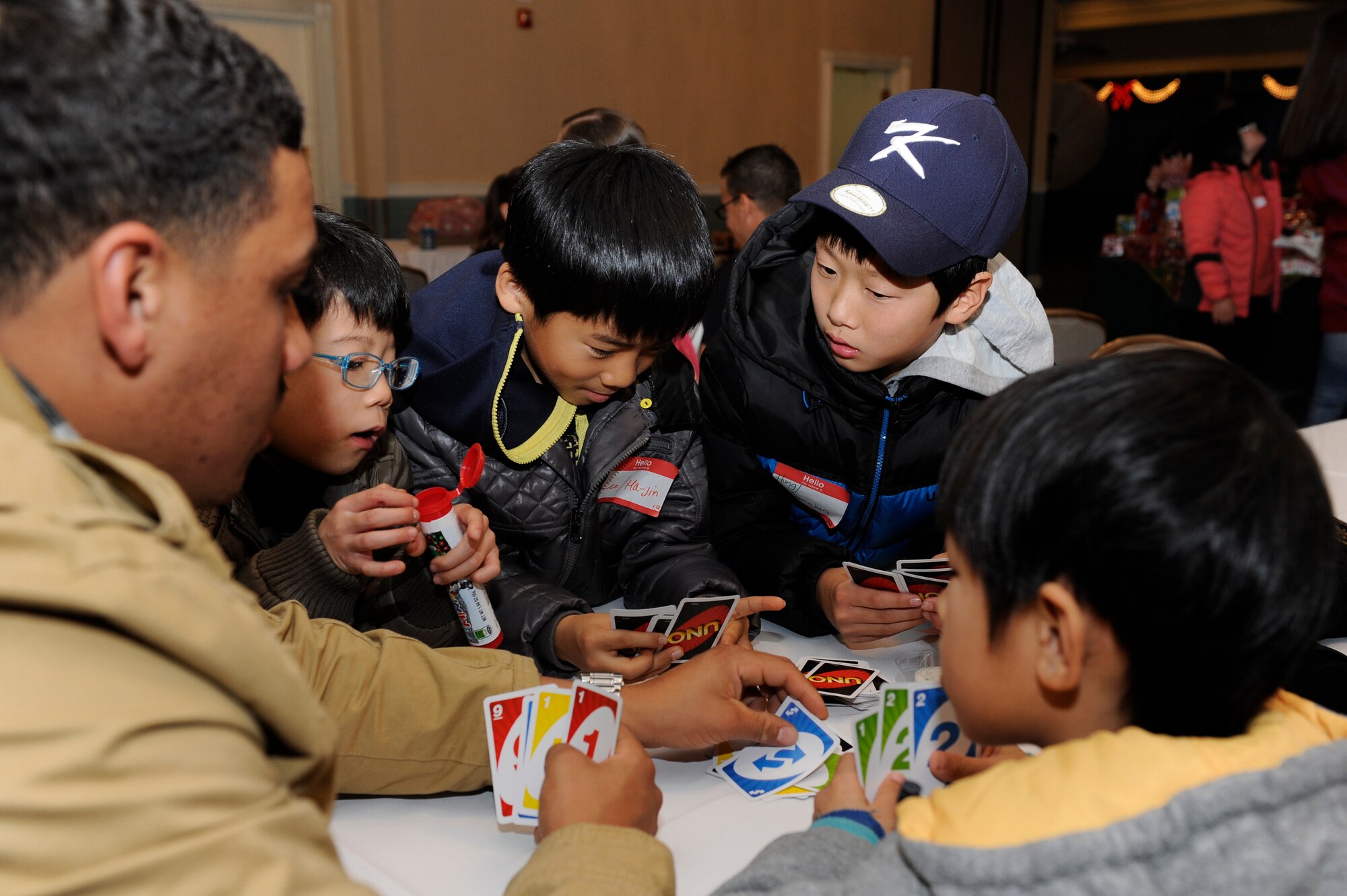 Senior Airman Mario Difranco, 8th Communications Squadron plays Uno with the children from Illmagwon Orphanage during a Christmas party at the Loring Club on Kunsan Air Base, Republic of Korea, Dec 1, 2012. The children  participated in many activities during the event including board games, coloring, musical chairs and opening presents. (U.S. Air Force photo by Marcus Morris/released)