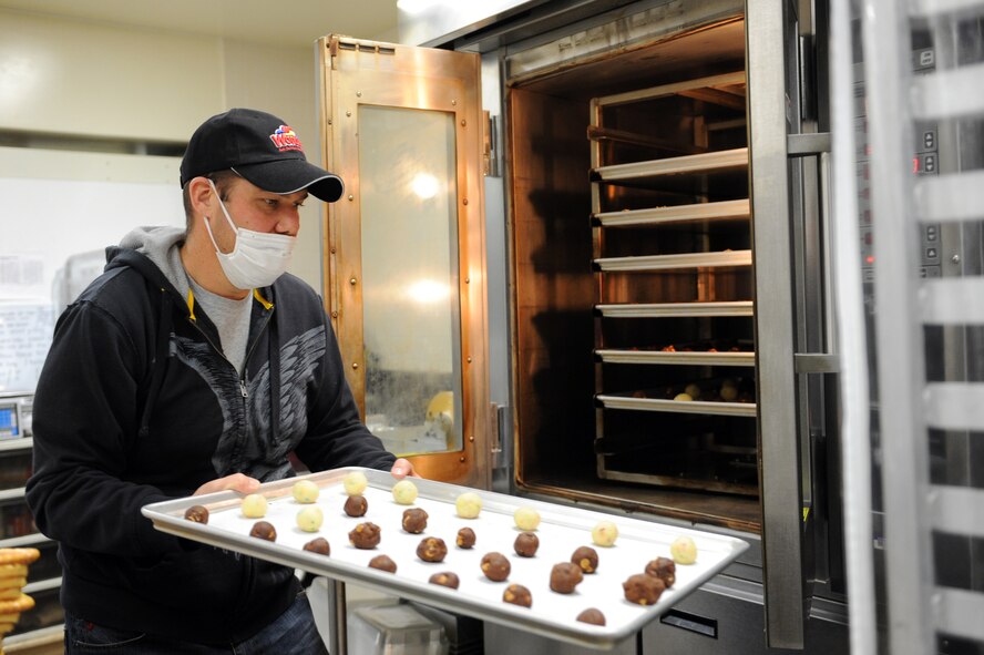 Matthew Whittaker, Defense Commissary Agency commissary officer, puts cookies in the oven during the base’s annual Cookie Caper at Misawa Air Base, Japan, Dec. 10, 2012. The commissary made an agreement with cookie caper volunteers that if they came with their cookie dough prepared, the commissary would provide the workspace, tables, baking sheets and oven. A total of 164 dozen cookies were baked at the commissary, which added to the base’s total of 2,650 dozen cookies. (U.S. Air Force photo/Airman 1st Class Kia Atkins) 


