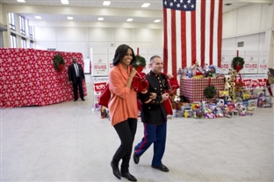 Marine Corps Staff Sgt. Joel Vazquez escorts First Lady Michelle Obama as she arrives with a sack full of toys at the Toys for Tots Distribution Center at Joint Base Anacostia-Bolling in Washington, D.C., Dec. 11, 2012. 