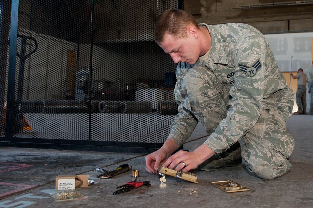Senior Airman Michael Maze, 28th Civil Engineer Squadron structures technician, sizes a cylinder of a lock on the gate surrounding the soon-to-be fitness area in the Pride Hangar on Ellsworth Air Force Base, S.D., Dec. 12, 2012. Ellsworth locksmiths are responsible for installing and overseeing the installation of every lock on base. (U.S. Air Force photo by Airman 1st Class Kate Thornton-Maurer/Released)
