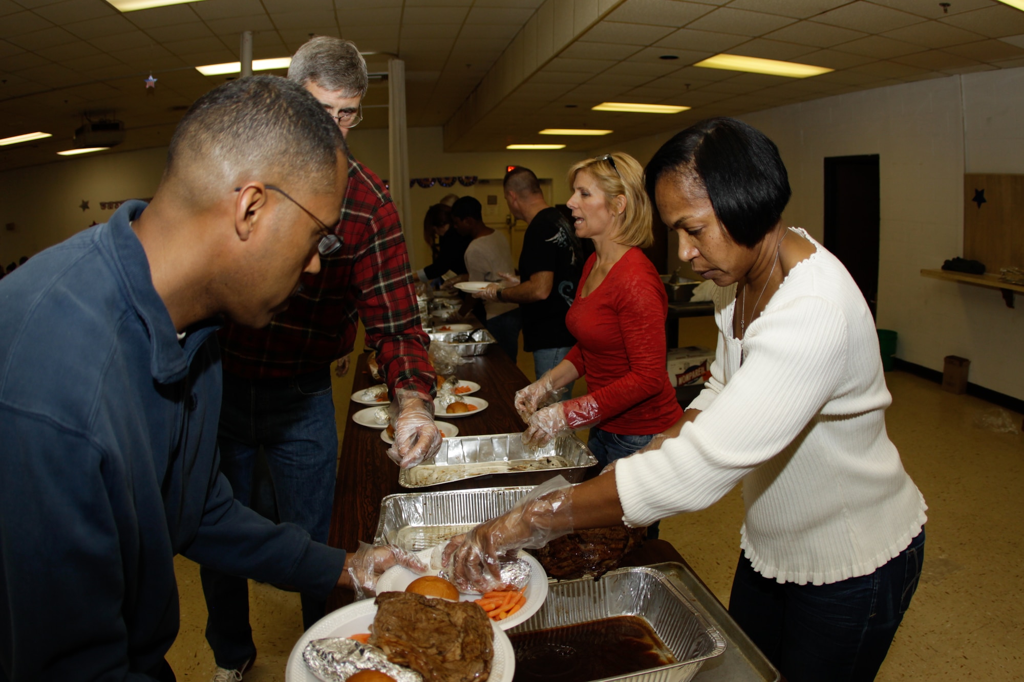 TINKER AIR FORCE BASE, Oklahoma – Members of the 507th Air Refueling Wing, 513th Air Control Group and the 137th Air Refueling Wing, Oklahoma Air National Guard gather around the serving line picking steak dinner plates for the 14th annual Operation Holiday Spirit fund raiser.  This year’s event, held at the Del City American Legion was its biggest ever.  Three hundred eleven people came out to raise over $34,000 through organization donations and auction items.  The charity event is to help out Airman families in need. 