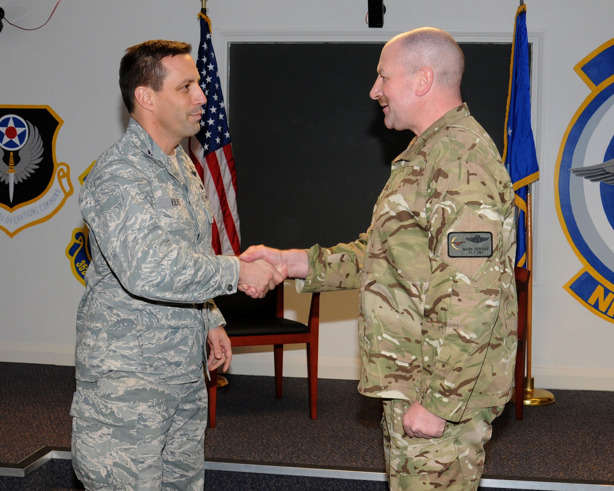 Col. Christopher Kulas, 100th Air Refueling Wing commander, coins Royal Air Force Flight Sgt. Mark Service Dec. 7, 2012, at RAF Mildenhall, England. He was coined in conjunction with winning a British-American Committee community relations award. (U.S. Air Force photo by Gina Randall/Released)