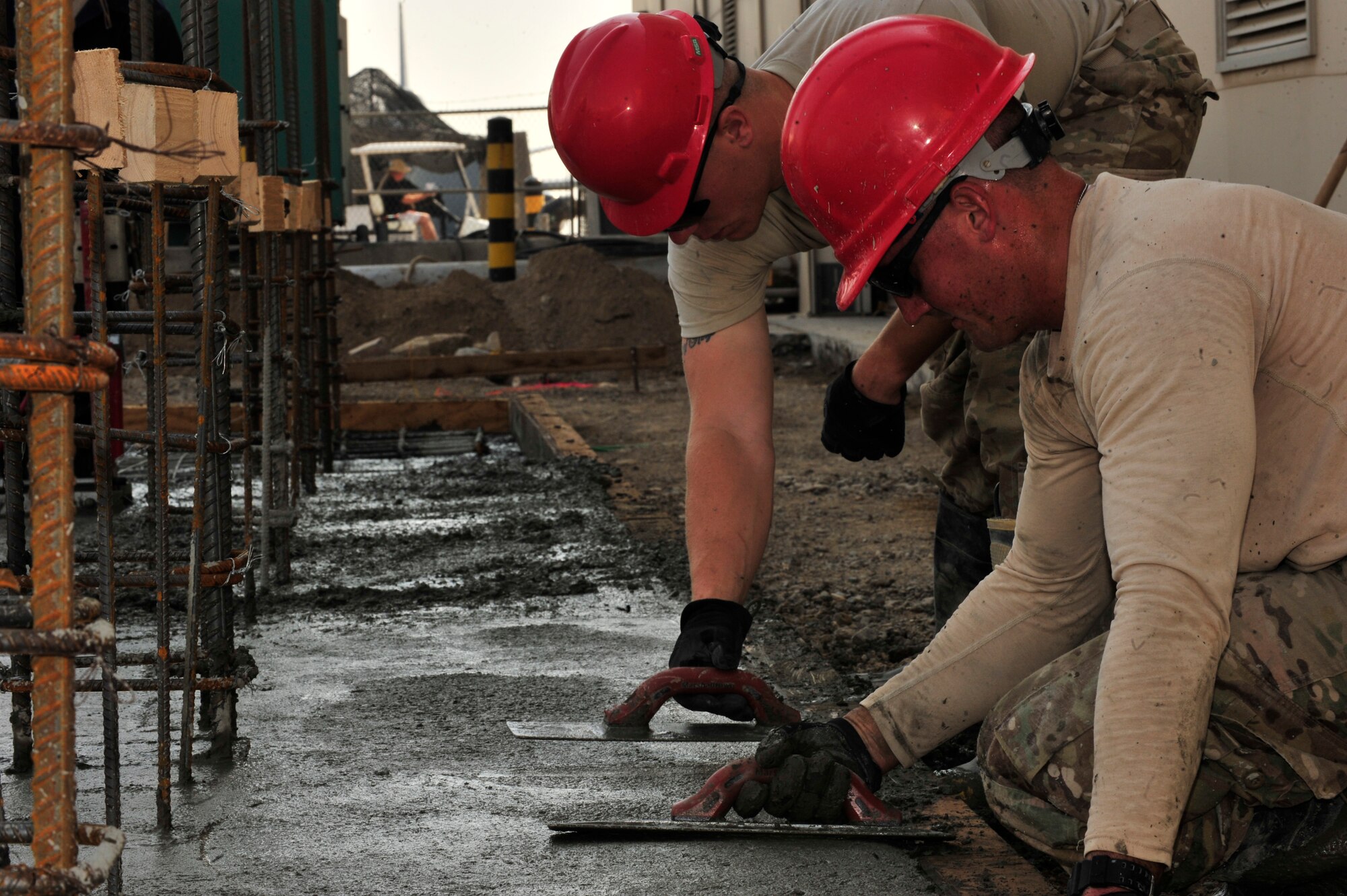 SOUTHWEST ASIA -- U.S. Air Force Senior Airman Tyler Vann, 560th RED HORSE Squadron structures journeyman, and Senior Airman John Fox, 560th RHS DIRTBOY, smooth recently poured concrete Dec. 4, 2012.  RED HORSE is comprised of specialized Airmen in 21 trades who deploy to austere and existing bases to build new facilities. (U.S. Air Force photo/Tech. Sgt. Christina M. Styer) (RELEASED)
