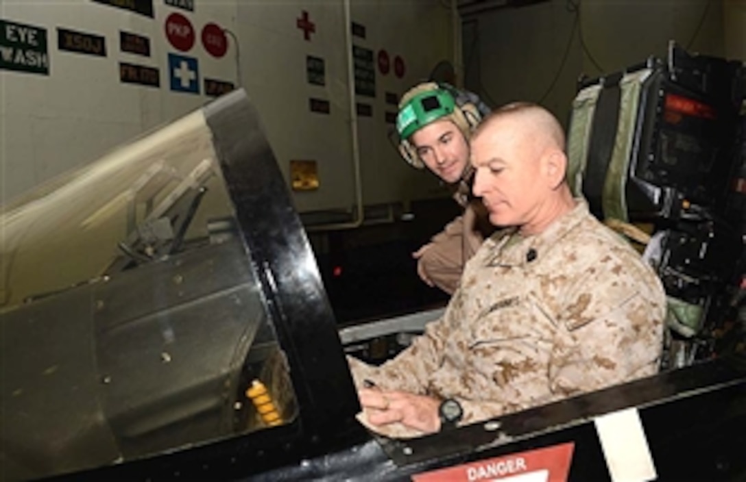 Marine Corps Sgt. Maj. Bryan Battaglia, senior enlisted advisor to the chairman of the Joint Chiefs of Staff, sits in the cockpit of an F/A-18E Super Hornet from the Tophatters of Strike Fighter Squadron 14 in the hangar bay of the aircraft carrier the USS John C. Stennis during a USO-sponsored holiday tour led by U.S. Army Gen. Martin E. Dempsey, chairman of the Joint Chiefs of Staff, in the Arabian Sea, Dec. 13, 2012. 