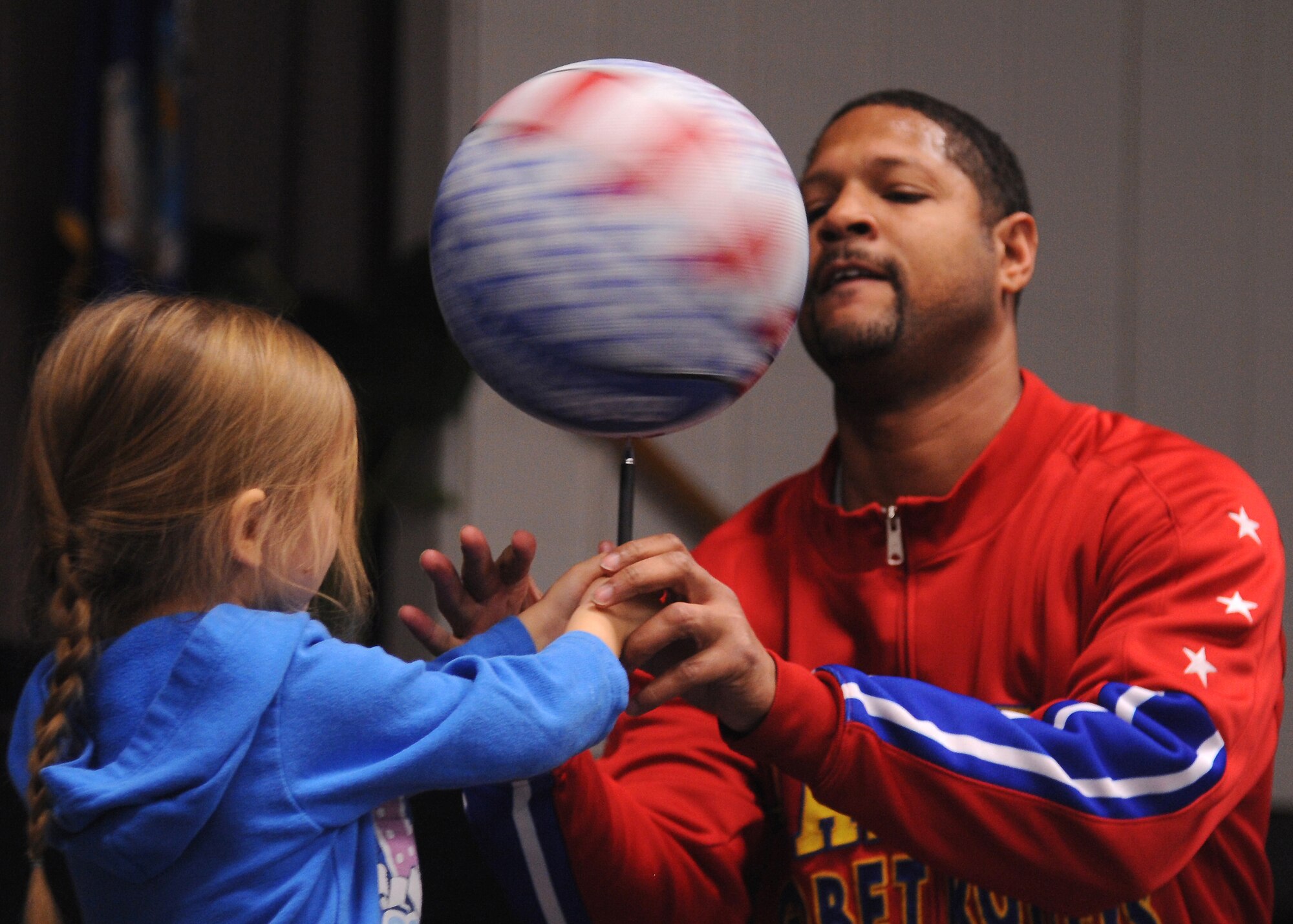 Harlem Globetrotter Chris “Handles” Franklin assists a child with spinning a basketball on the point of a pen Dec. 11, 2012, at the Community Activity Center on Grand Forks Air Force Base, N.D. Handles used his basketball skills to entertain and teach an audience of approximately 50 adults and children about the ABCs of Bullying Prevention.  The Globetrotters designed the community outreach program in coordination with the National Campaign to Stop Violence. The ABCs of Bullying Prevention stands for Action, Bravery, and Compassion. (U.S. Air Force photo/Airman 1st Class Xavier Navarro)