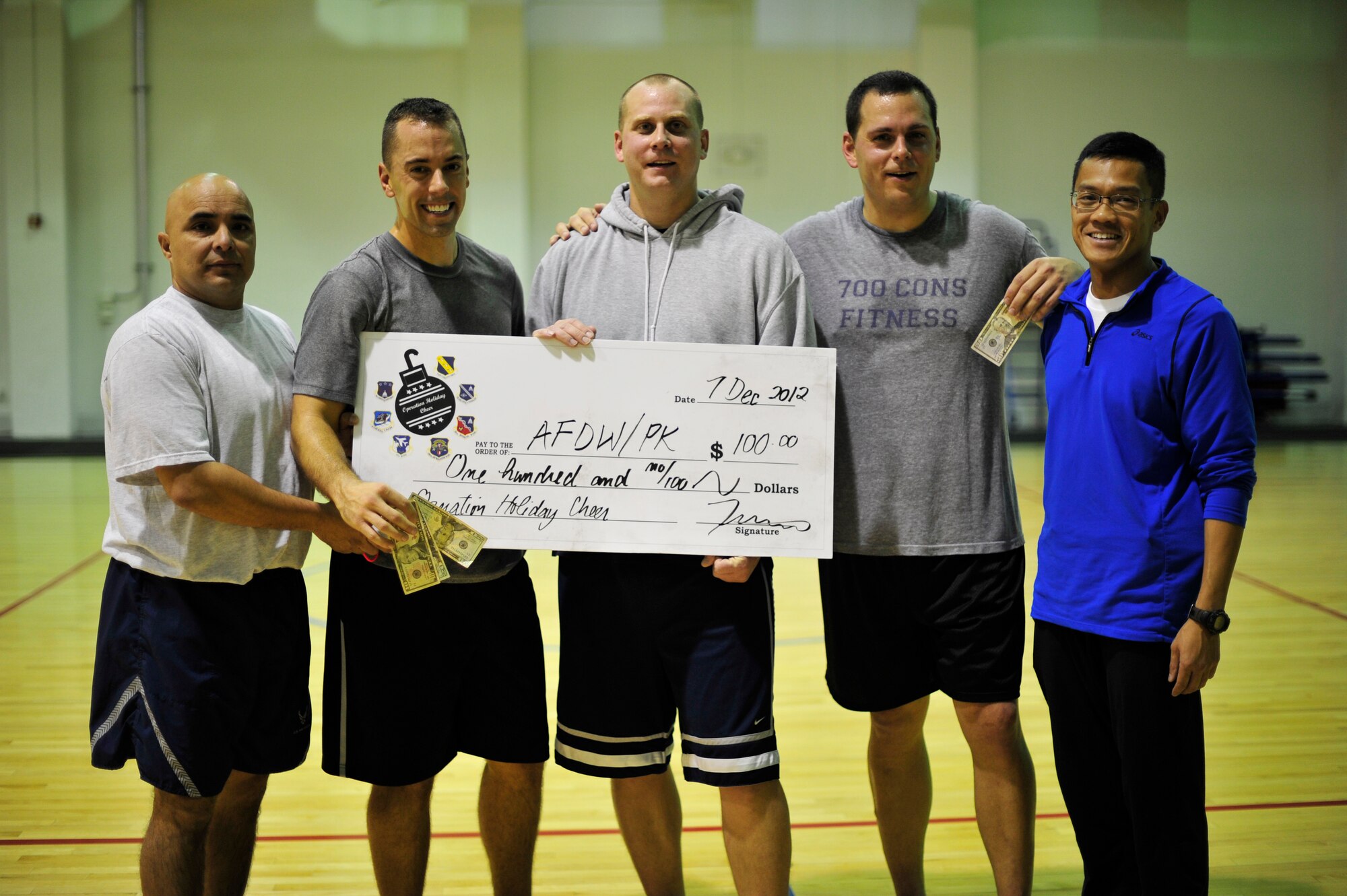 The 11th Civil Engineer Squardon Operations team accepts a $300 check for placing 1st in the 3-on-3 basketball tournament at the East Fitness Center, Dec. 7, 2012. The tournament was held as a part of “Operation Holiday Cheer,” which aimed to promote unity and teamwork between Joint Base Andrews military members. (U.S. Air Force photo/ Airman 1st Class Erin O’Shea)