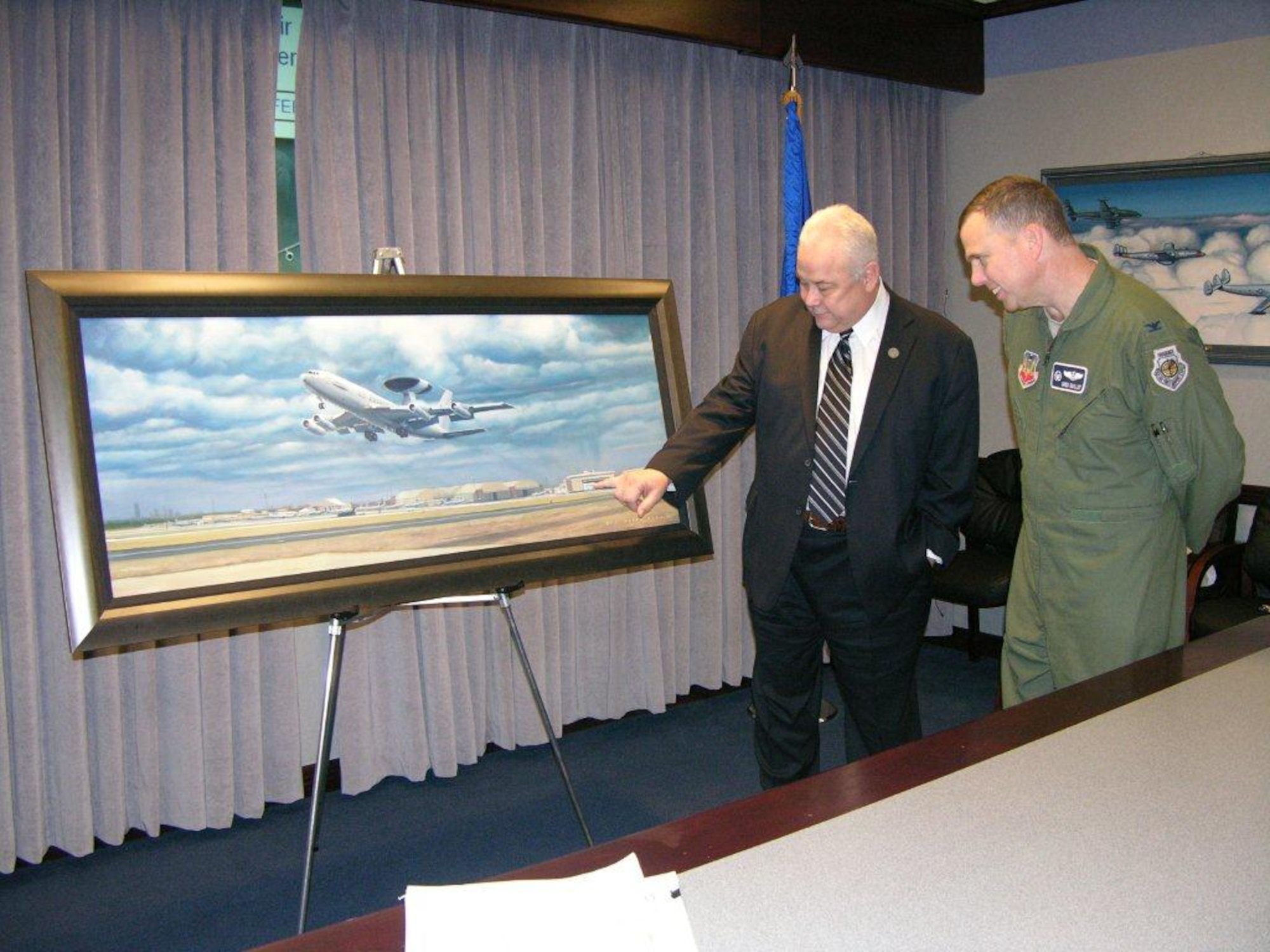 Bill Richards, left, representing the local Airborne Early Warning Association, presents Col. Greg Guillot, 552nd Air Control Wing commander, with a framed painting of an E-3 “Sentry” Airborne Warning and Control Systems aircraft by Tinker artist Darby Perrin celebrating the 35th anniversary of the E-3 prior to the wing’s bi-weekly staff meeting Dec. 6 in the 552nd ACW headquarters building. Mr. Perrin is also a senior master sergeant with the 507th Air Refueling Wing, serving as a boom operator on the KC-135 “Stratotanker” at Tinker. (Air Force photo by Darren D. Heusel)
