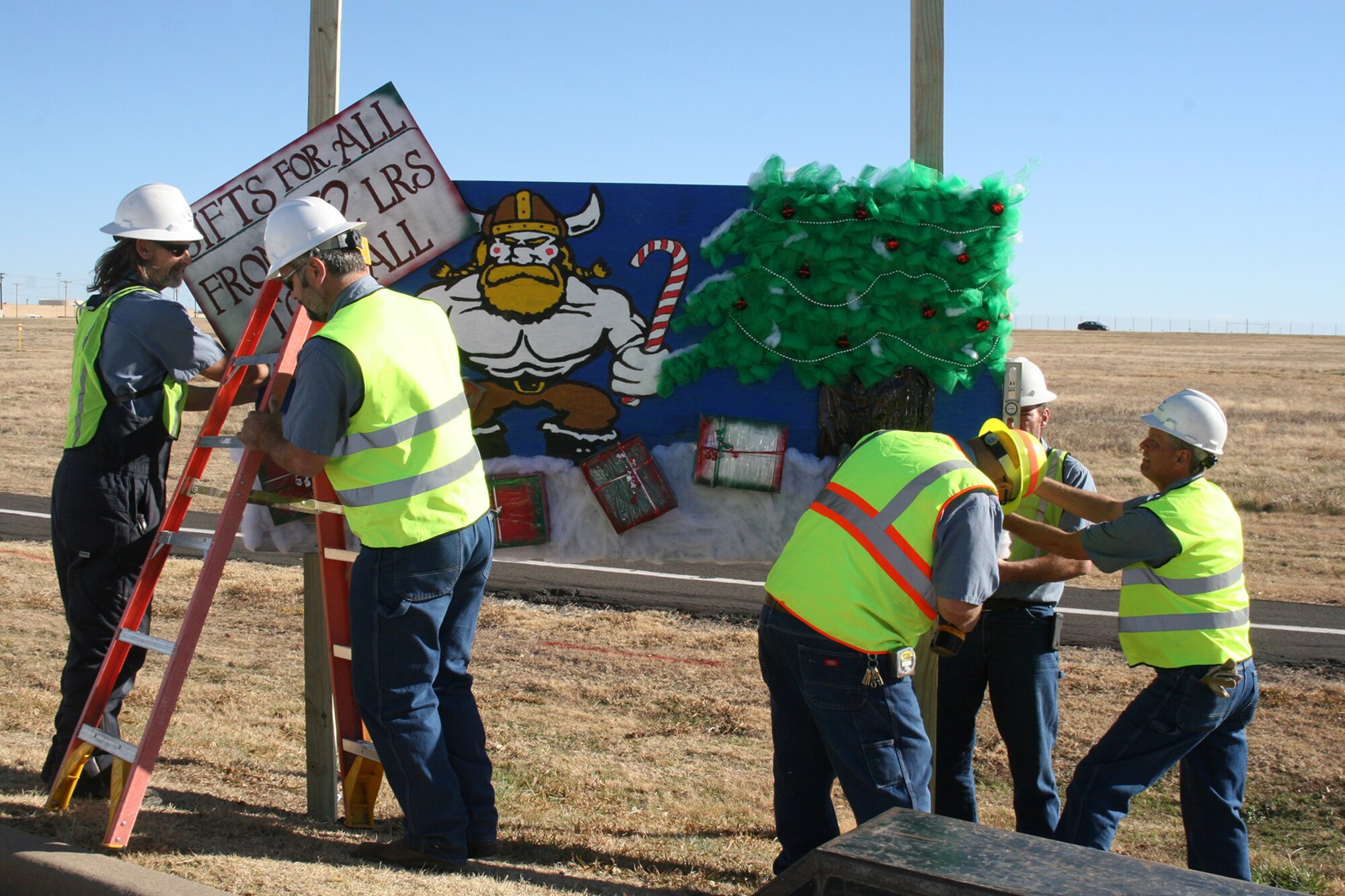 A.L. Smith, Gregory Garrison, Rodney Crawford, Dewey Sanford and Eddie Boyd, all with the 72nd Air Base Wing Civil Engineering Directorate, place one of the 28 holiday cards that line both sides of Arnold Street near the Tinker Golf Course. The theme of this year’s card contest is “Squadron Spirit.” (Air Force photo by Becky Pillifant)