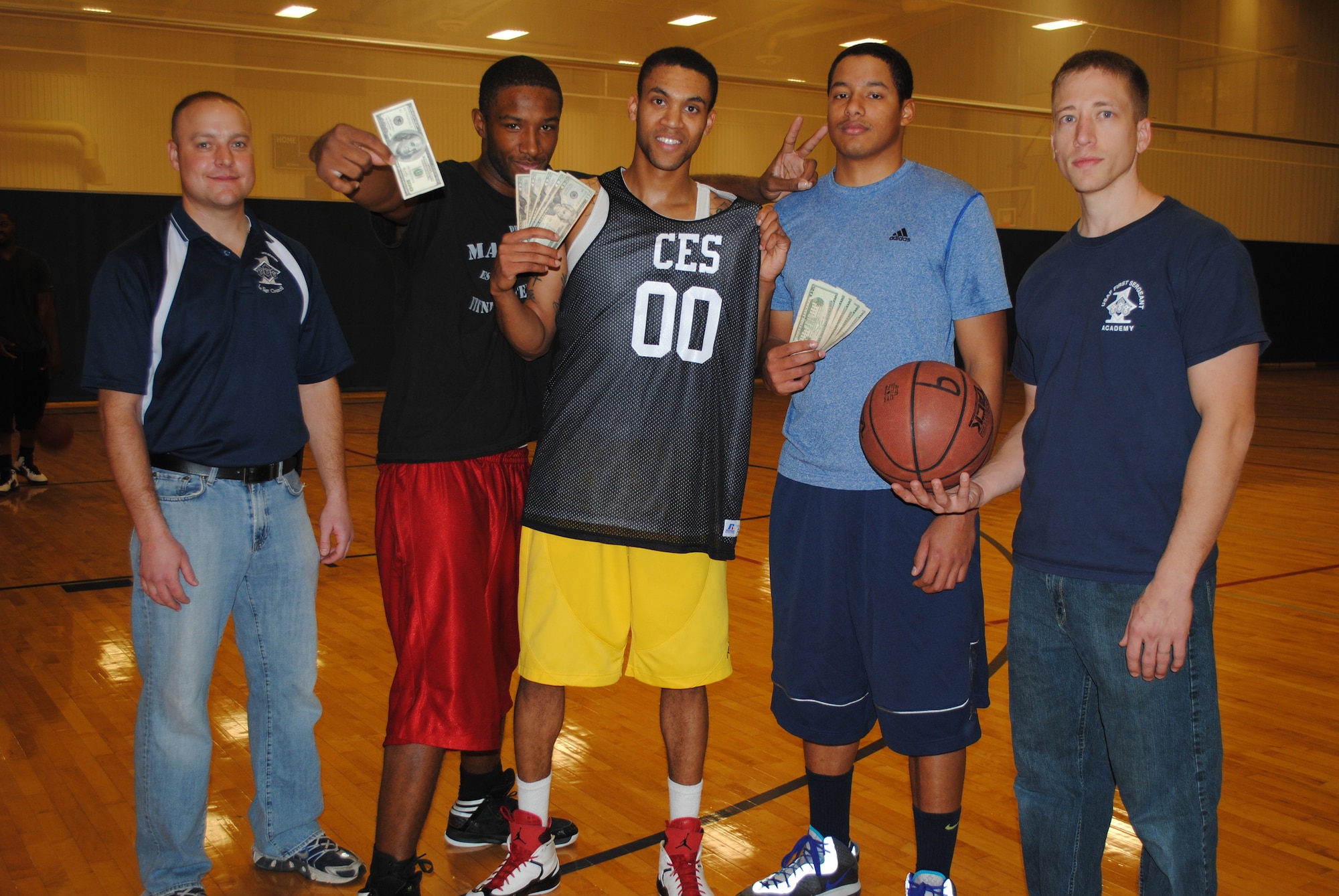 Members of the 341st Civil Engineer Squadron (center) pose with their $300 first-place prize for winning a three-on-three basketball tournament on Dec. 10 at the Fitness Center for this year’s Operation Holiday Cheer. Pictured from left to right are Master Sgt. William Baccus, 341st CES; Airmen 1st Class Matthew Gambrell; Justin Long; Booker Hinton, all 341st CES members; and Master Sgt. Jeremiah Martin, 341st Operations Group. Anyone who participated in the dodgeball, soccer, scavenger hunt, bowling and basketball OHC tournaments were eligible to win the grand prize that was given away at the OHC Wrap-Up Party at the Grizzly Bend on Dec. 12. (U.S. Air Force photo/Airman 1st Class Katrina Heikkinen) 