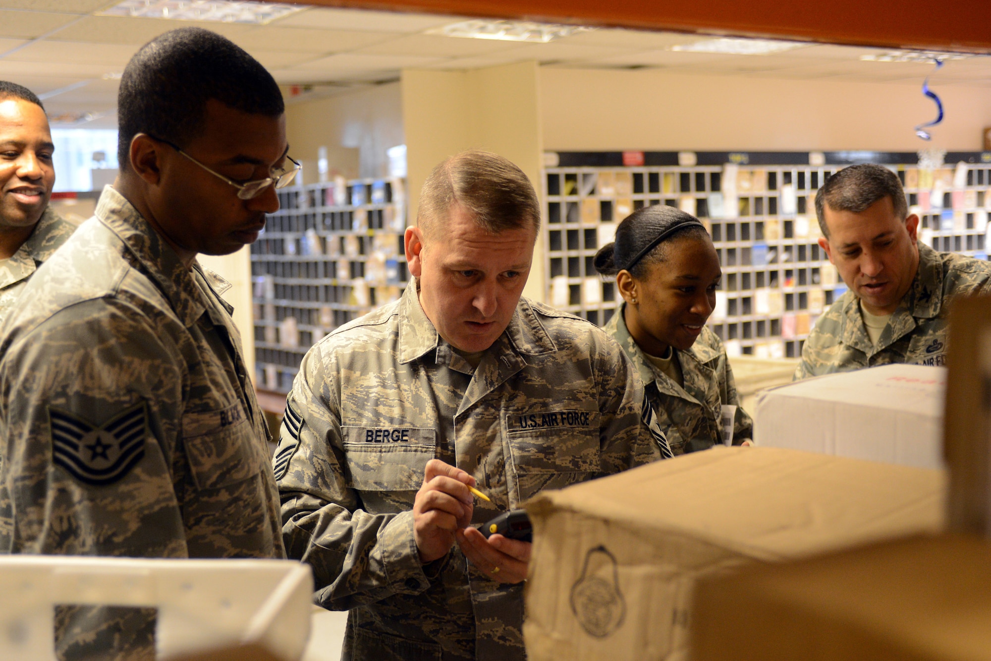 RAF MENWITH HILL, United Kingdom - Tech. Sgt. Phillip Black, 421st Air Base Group postmaster, shows Chief Master Sgt. Scott Berge, 501st Combat Support Wing command chief, how to scan packages into the tracking system during a holiday visit to the post office at RAF Menwith Hill Dec. 13. (U.S.Air Force photo by Staff Sgt. Debbie Lockhart)