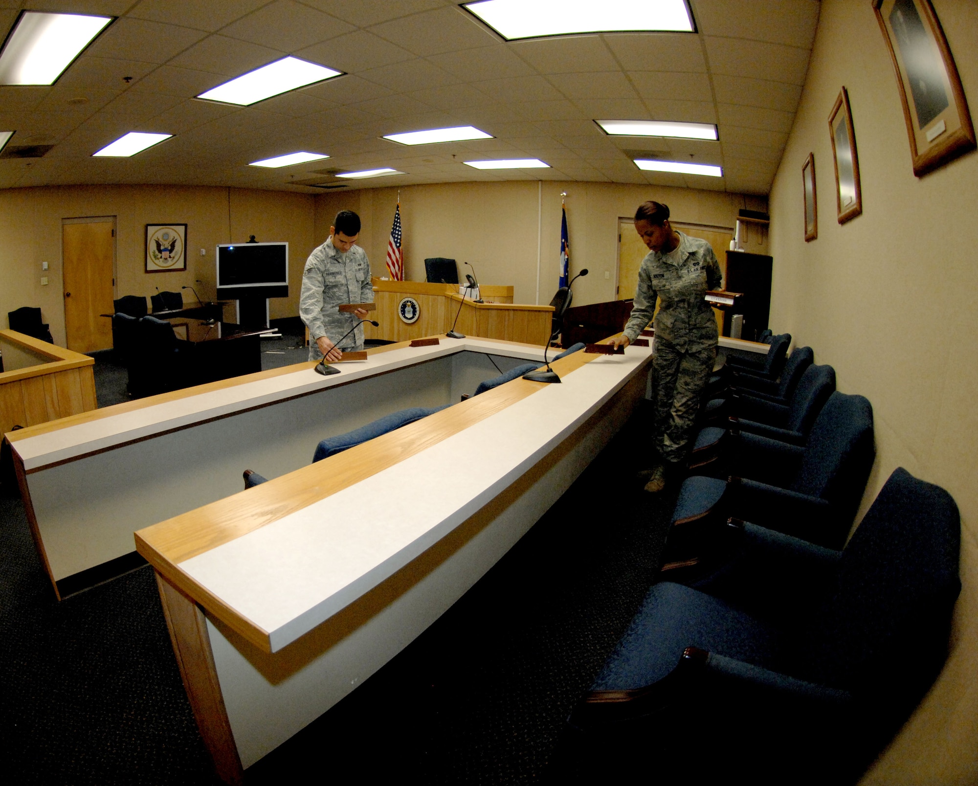 U.S. Air Force Senior Airman Diego Bermudez and Airman 1st Class Margo Bolton, both from the 355th Fighter Wing Legal Office, set out name plates in preparation of court-martial proceedings on Davis-Monthan Air Force Base, Ariz., Dec. 10, 2012. Before a trial, paralegals take steps to ensure the courtroom is prepared, such as cleaning and setting out water. (U.S. Air Force photo by Airman 1st Class Saphfire Cook)