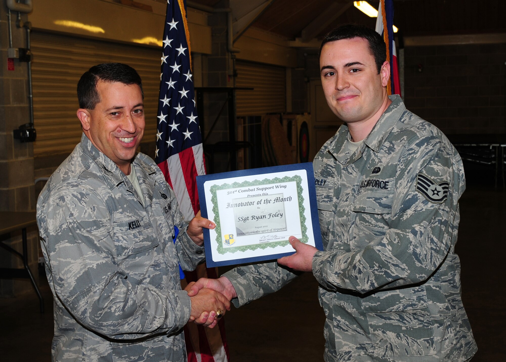RAF MENWITH HILL, United Kingdom -- Col. Brian Kelly, 501st Combat Support Wing commander, presents Staff Sgt. Ryan Foley, 421st Air Base Group communications flight, with the Innovator of the Month Award at RAF Menwith Hill, Sept. 25. Foley devised a plan and deployed a $40,000 network management suite that resulted in savings of $100,000 from the squadron's annual budget due to a reduction in extended maintenance contracts. (U.S. Air Force photo by Staff Sgt. Brok McCarthy)
