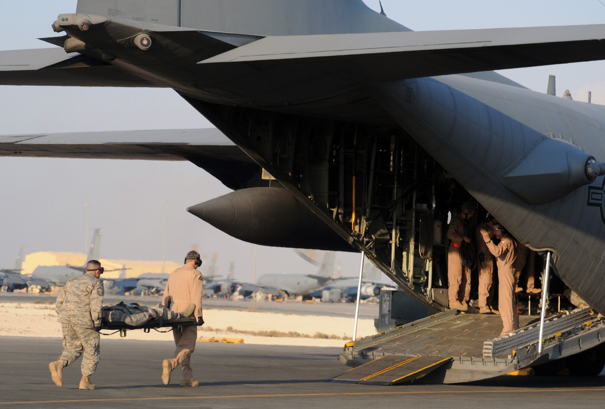 SOUTHWEST ASIA - Capt. Jason Price, 379th Expeditionary Aeromedical Evacuation Squadron flight nurse, waves litter bearers, Brig. Gen. Roger H. Watkins, 379th Air Expeditionary Wing commander, and Senior Master Sgt. Augustin Ortiz, 379th EAES technician, onto a C-130 during a mock 379th EAES engines running on-load mission Dec. 4. (U.S. Air Force photo/Capt. Angela Webb)