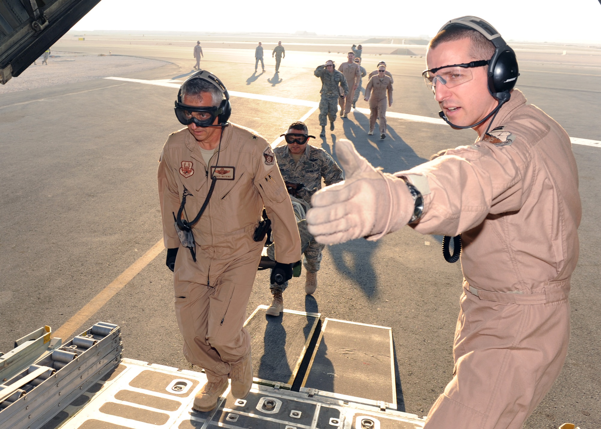 SOUTHWEST ASIA - Capt. Jason Price (right), 379th Expeditionary Aeromedical Evacuation Squadron flight nurse, signals Brig. Gen. Roger H. Watkins, 379th Air Expeditionary Wing commander, to carry his patient onto the aircraft during an engines running on-load mission Dec. 4. The 379th AEW commander, vice commander and command chief participated in the mock exercise to have a better understanding of the unit's mission. (U.S. Air Force photo/Senior Airman Joel Mease)