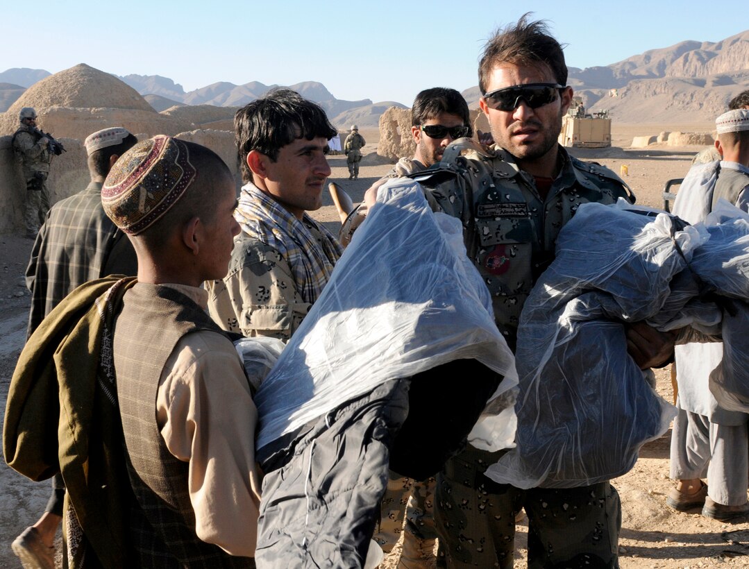 Lt. Abdul Azim Nooree, an officer with the Afghan Border Police, hands out blankets and clothing to children in the village of Gagre Naw, Afghanistan, during Operation Southern Strike IV, Nov. 18, 2012. More than 4,400 pounds of flour, rice, blankets and clothing were delivered to remote villages in Spin Boldak and Tak-the Pol Districts by Afghan Air Force Kandahar Air Wing Mi-17 helicopter crew members and the Afghan Border Police. (U.S. Army Photo/Staff Sgt. Ryan Sheldon)