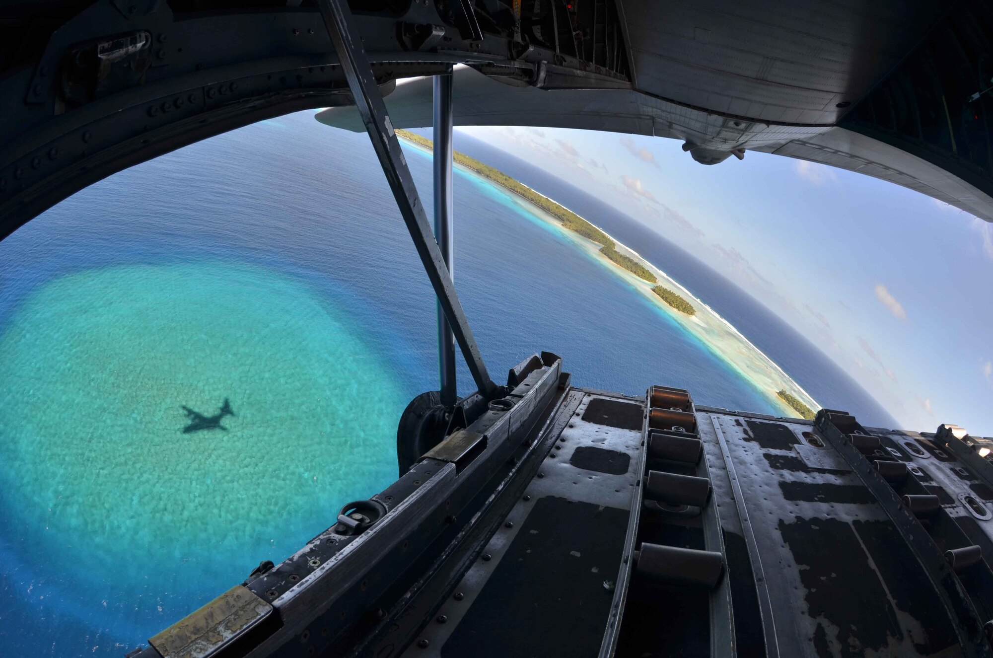A Federated States of Micronesia island is seen in the distance as a U.S. Air Force C-130 Hercules turns back to ensure reception of a box of humanitarian assistance goods during an Operation Christmas Drop flight from Andersen Air Force Base, Guam, Dec. 14, 2012. Each year OCD provides aid to more than 30,000 islanders in Chuuk, Palau, Yap, Marshall Islands and Commonwealth of the Northern Mariana Islands. This year is the 61st anniversary of OCD, making it the longest running humanitarian mission in the world. In total, there are eight planned days of air drops, with 54 islands scheduled to receive humanitarian aid. (U.S. Air Force photo/Staff Sgt. Alexandre Montes/Released)