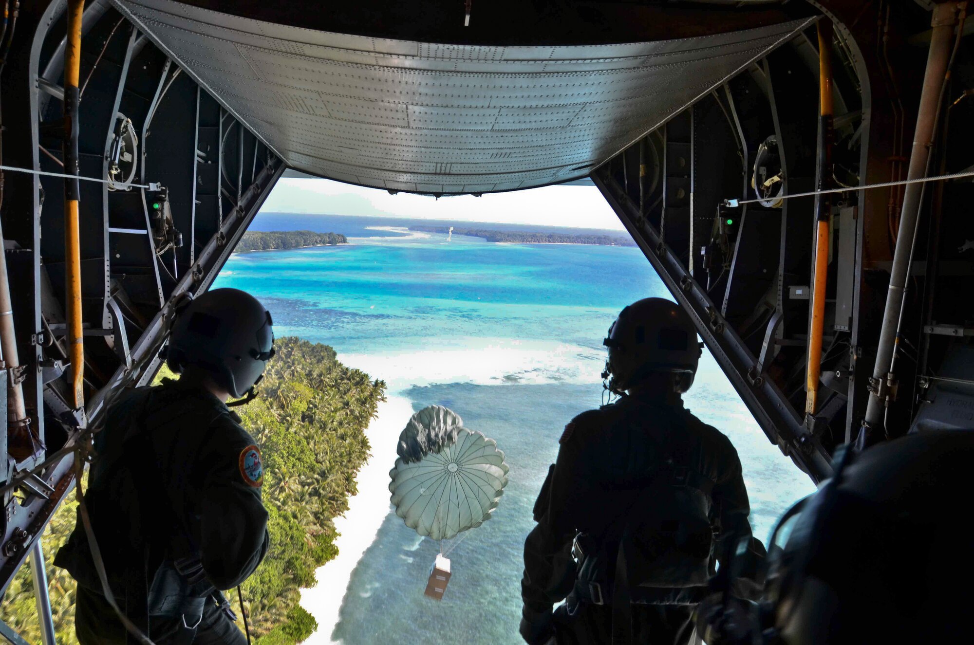 Senior Airman Timothy Oberman, 36th Airlift Squadron loadmaster, left, and Staff Sgt. Nick Alarcon, 36th Airlift Squadron instructor loadmaster, watch after pushing a box of humanitarian assistance goods out of a U.S. Air Force C-130 Hercules during an Operation Christmas Drop flight from Andersen Air Force Base, Guam, Dec. 14, 2012. Each year OCD provides aid to more than 30,000 islanders in Chuuk, Palau, Yap, Marshall Islands and Commonwealth of the Northern Mariana Islands. This year is the 61st anniversary of OCD, making it the longest running humanitarian mission in the world. In total, there are eight planned days of air drops, with 54 islands scheduled to receive humanitarian aid. (U.S. Air Force photo/Staff Sgt. Alexandre Montes/Released)