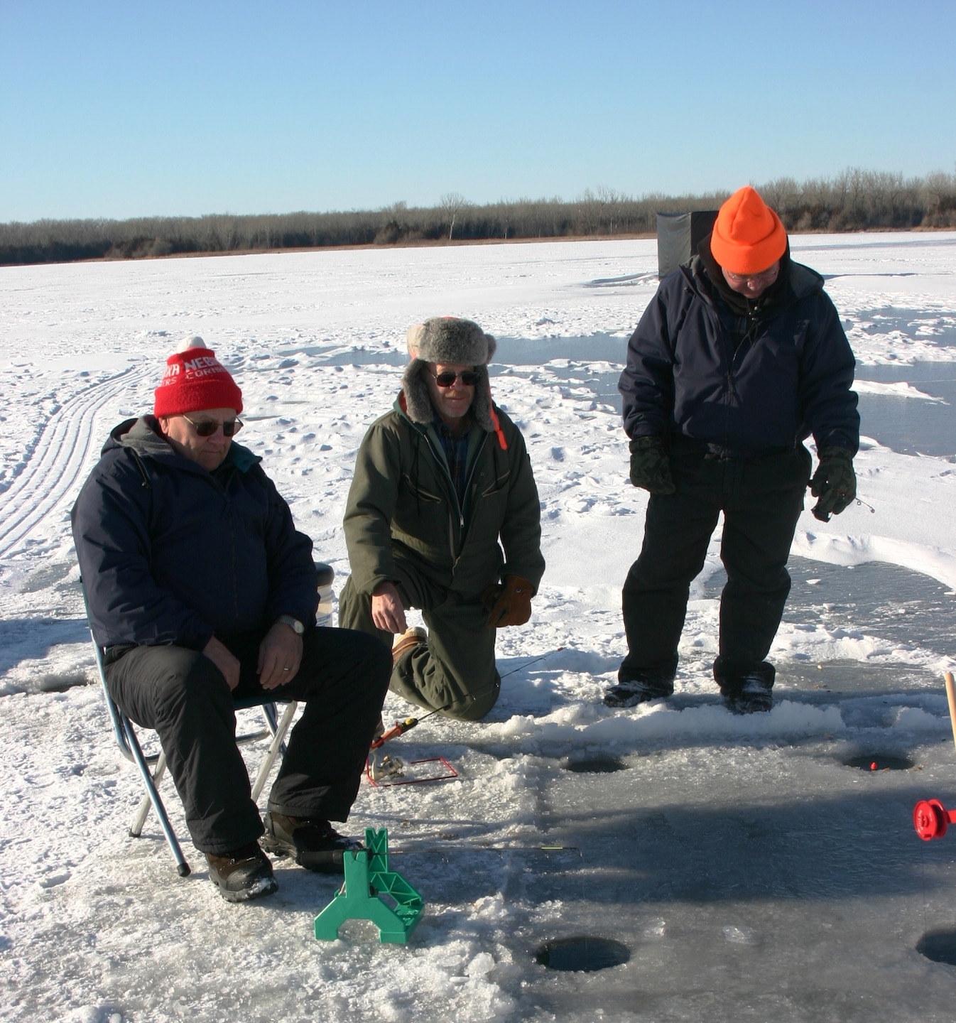 Theee men ice fishing.