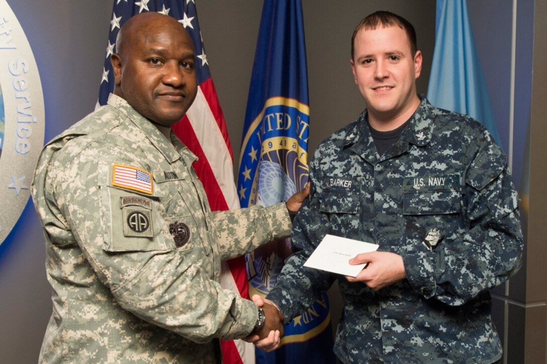 FORT GEORGE G. MEADE, Md. - U.S. Army Command Sgt. Maj. Patrick Alston, senior enlisted leader at USSTRATCOM, presents U.S. Navy Petty Officer 2nd Class Andrew Barker with a coin and letter on behalf of the command Dec. 14. Ten USCYBERCOM enlisted personnel were recognized for their contributions to the USCYBERCOM mission of the operation and defense of DoD networks.