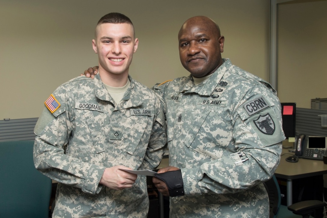 FORT GEORGE G. MEADE, Md. - U.S. Army Command Sgt. Maj. Patrick Alston, senior enlisted leader at USSTRATCOM, presents U.S. Army Pfc. Tyler Goodman with a coin and letter on behalf of the command Dec. 14. Ten USCYBERCOM enlisted personnel were recognized for their contributions to the USCYBERCOM mission of the operation and defense of DoD networks.