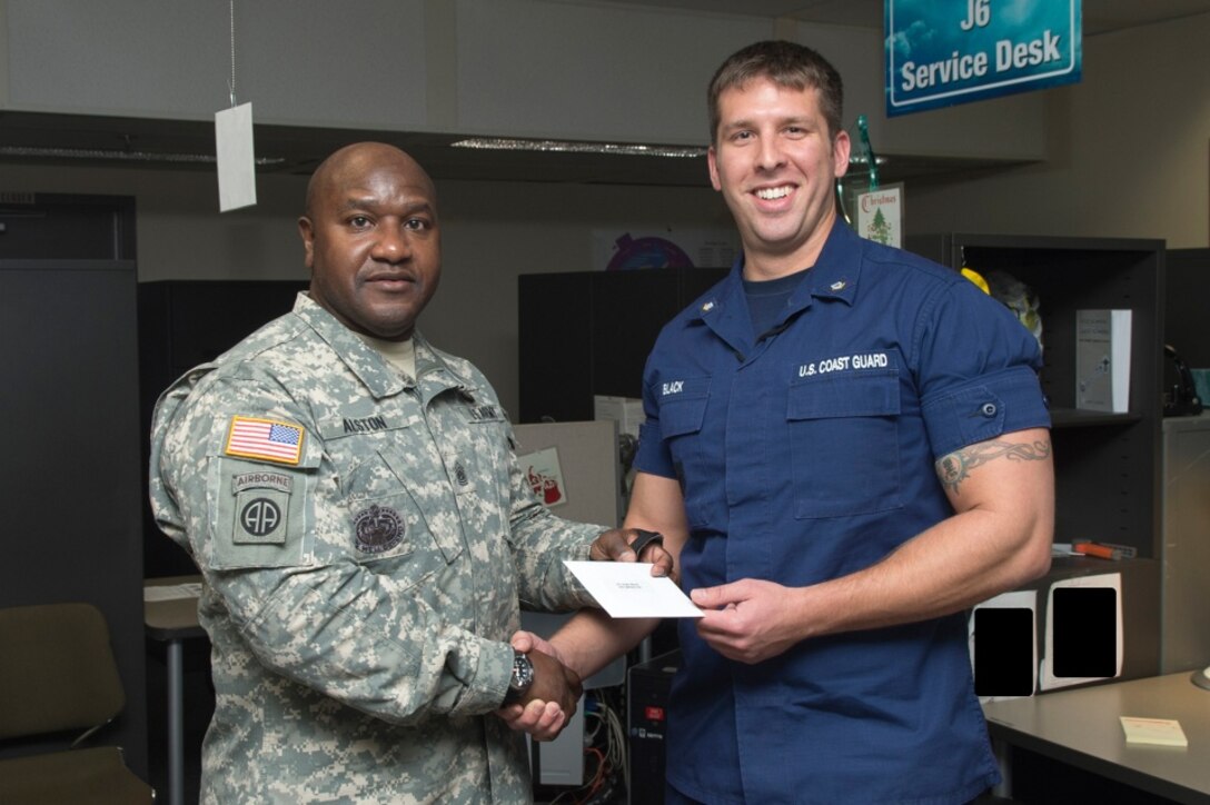 FORT GEORGE G. MEADE, Md. - U.S. Army Command Sgt. Maj. Patrick Alston, senior enlisted leader at USSTRATCOM, presents U.S. Coast Guard Petty Officer 3rd Class Kyle Black with a coin and letter on behalf of the command Dec. 14. Ten USCYBERCOM enlisted personnel were recognized for their contributions to the USCYBERCOM mission of the operation and defense of DoD networks.