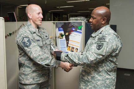 FORT GEORGE G. MEADE, Md. - U.S. Army Command Sgt. Maj. Patrick Alston, senior enlisted leader at USSTRATCOM, presents U.S. Air Force Master Sgt. Matthew Towers with a coin and letter on behalf of the command Dec. 14. Ten USCYBERCOM enlisted personnel were recognized for their contributions to the USCYBERCOM mission of the operation and defense of DoD networks.
