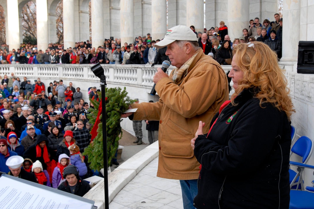 Morrill Worcester and his wife Karen, founder and executive director, Wreaths Across America, addresses thousands of service members and volunteers during the opening ceremony and presents Mary Byers, president of the Gold Star Mothers, with the "Millionth", wreath at the apatheater at Arlington National Cemetery in Arlington, Va., Dec. 15, 2012. Thousands of volunteers helped place 110,000 wreaths at the graves of fallen service members as part of the annual Wreaths Across America event.