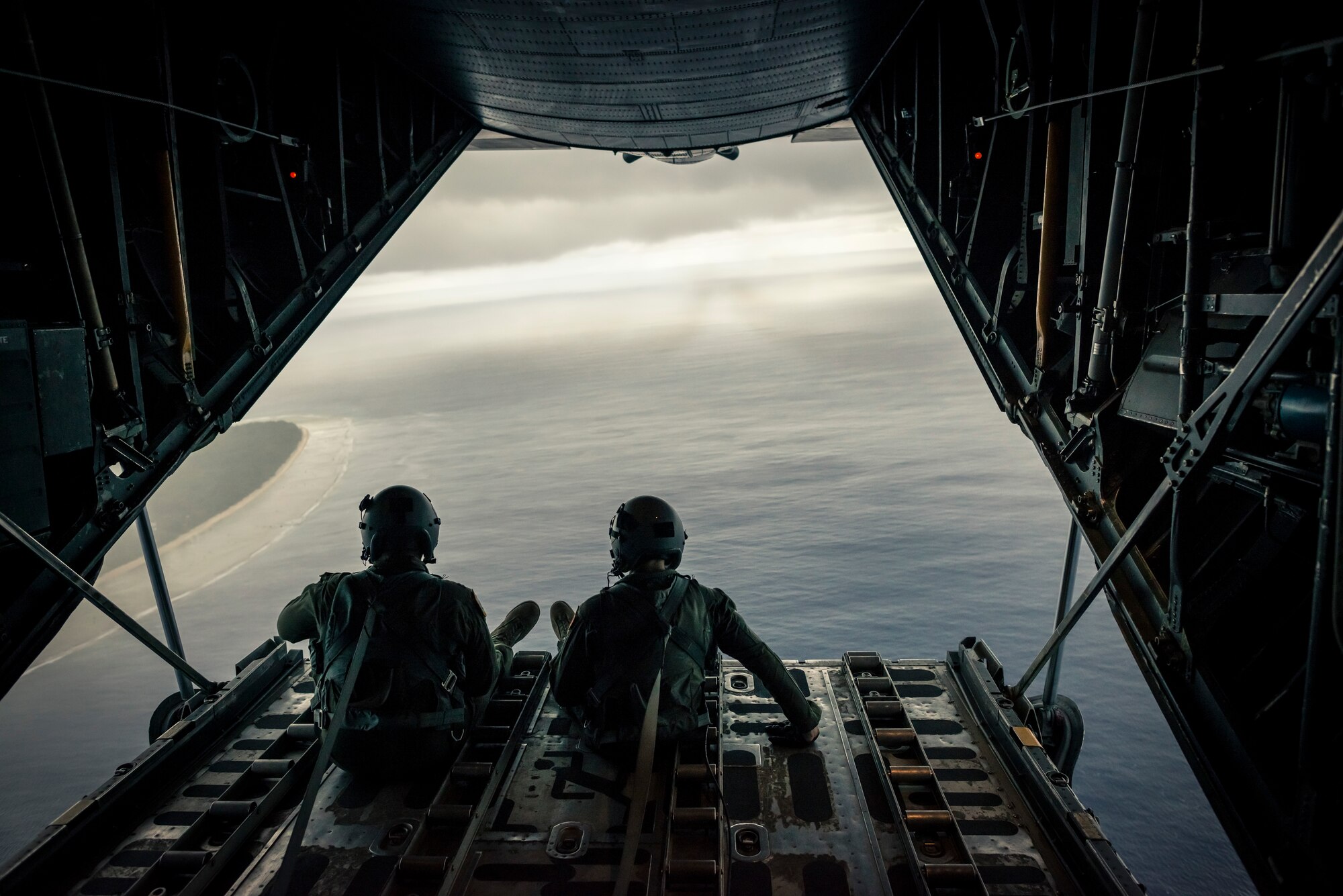 OVER THE PACIFIC OCEAN -- Capt. Ryan Turonek, left, and Senior Airman Timothy Oberman, 36th Airlift Squadron, sit on the back ramp of a C-130 Hercules after a successful low-cost, low altitude drop during Operation Christmas Drop Dec. 13, 2012. While used as a training opportunity for C-130 crews, each crew member expressed how gratifying it was to make a difference in the lives of the Pacific islanders they dropped humanitarian aid to. (U.S. Air Force photo by Tech. Sgt. Samuel Morse)