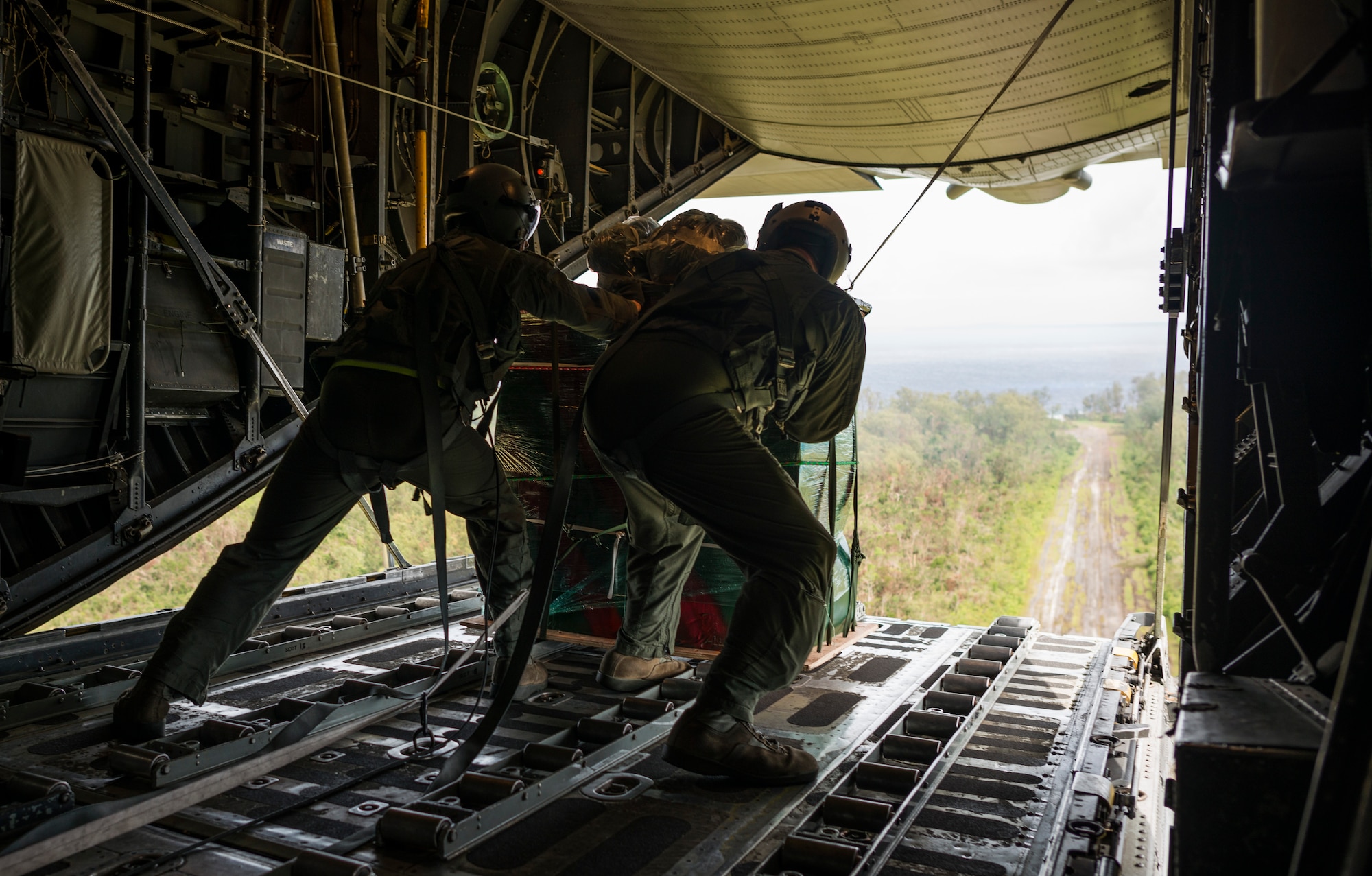 OVER THE PACIFIC OCEAN -- Senior Airman Timothy Oberman, left, and Capt. Ryan Turonek, 36th Airlift Squadron, push a bundle of humanitarian aid out the back of a C-130 Hercules during Operation Christmas Drop Dec. 13, 2012. Riggers from the 374th Logistics Readiness Squadron decorated some of the bundles with Christmas colors and wrote holiday greetings to the islanders on the skid plates. (U.S. Air Force photo by Tech. Sgt. Samuel Morse)