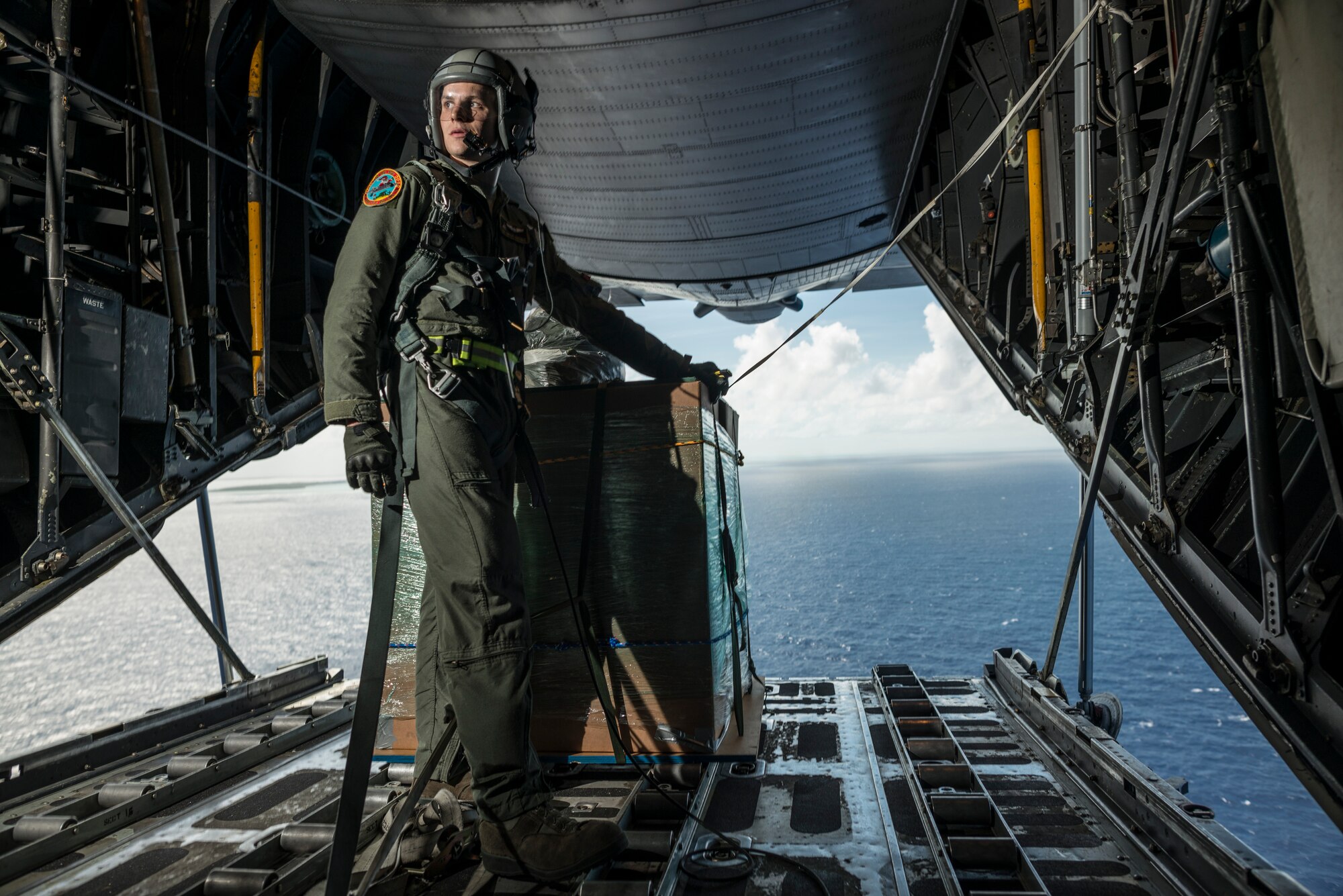 OVER THE PACIFIC OCEAN -- Senior Airman Timothy Oberman, 36th Airlift Squadron loadmaster, waits to drop a bundle of humanitarian aid during Operation Christmas Drop, Dec. 13, 2012. Timing is essential for low-cost, low-altitude air drops, often offering a window of only one or two seconds for the navigator to tell the loadmaster to drop the bundle once the drop zone is reached. (U.S. Air Force photo by Tech. Sgt. Samuel Morse)