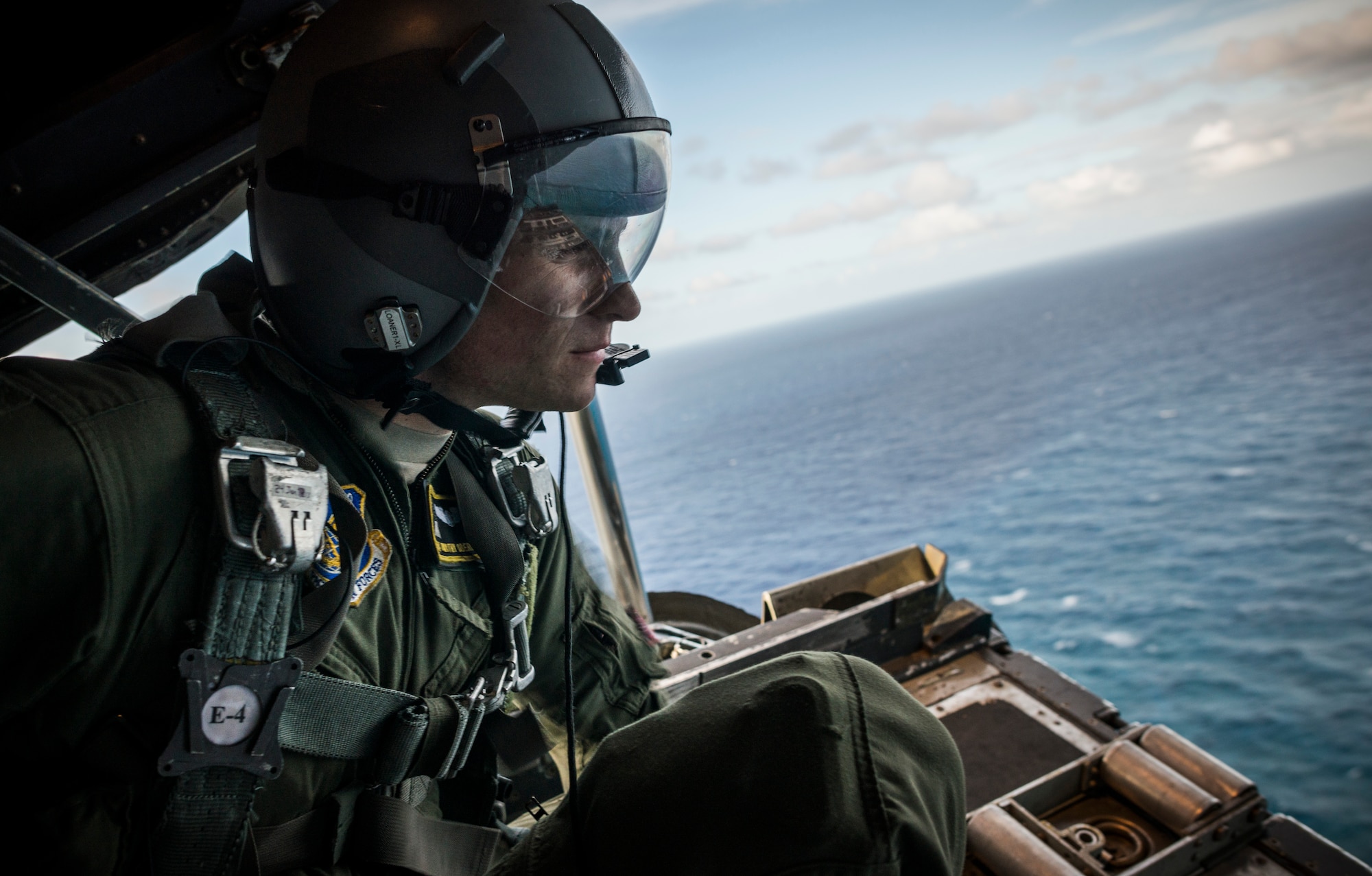 OVER THE PACIFIC OCEAN -- Senior Airman Timothy Oberman, 36th Airlift Squadron loadmaster, looks out over a drop zone from a C-130 Hercules after delivering humanitarian bundles to the island of Ulal, Dec. 11, 2012. Loadmasters are responsible for most of what happens in the back of a C-130, taking care of passengers, securing cargo and assisting the flight deck with takeoff and landing procedures. (U.S. Air Force photo by Tech. Sgt. Samuel Morse)