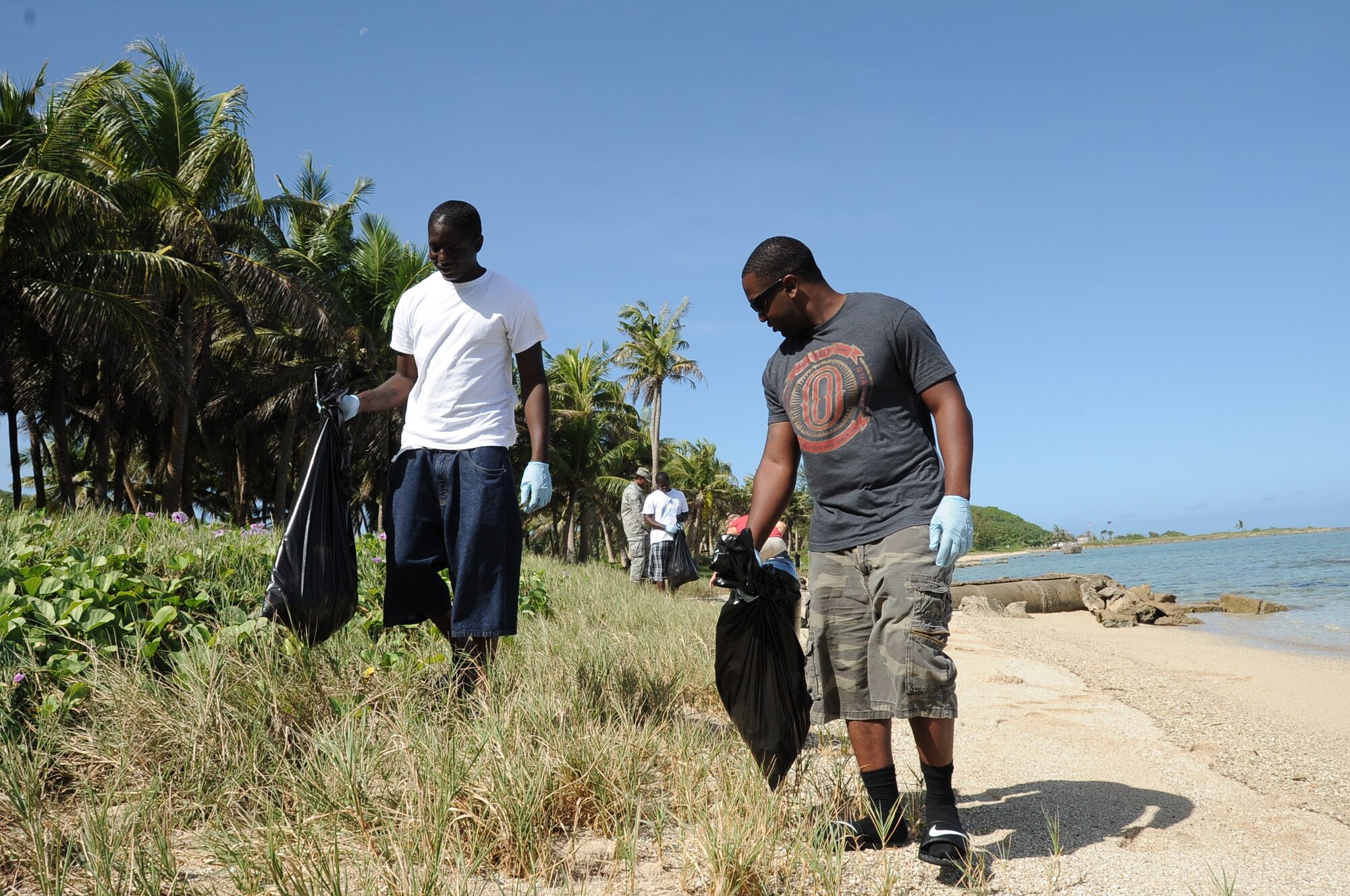 Airman 1st Class Gregory Jones-Fields, (left), and Airman 1st Class Keith Kennedy, both weapons personnel from the 36th Maintenance Squadron, participate in a beach cleanup at Asan Beach, Guam, Dec. 7, 2012, as part of their Weapons Day of Caring. The cleanup was organized in remembrance of the attacks on Pearl Harbor Dec. 7, 1941. (U.S. Air  Force photo by Airman 1st Class Adarius Petty/Released)