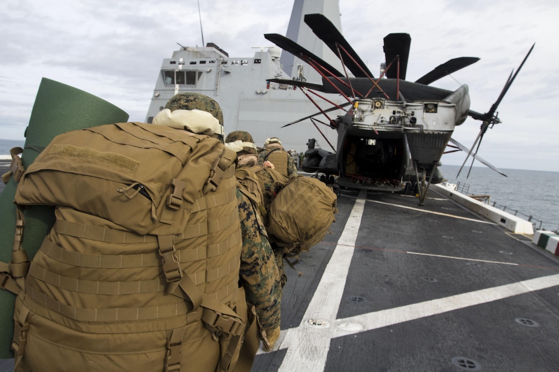 Marines with the 26th Marine Expeditionary Unit's (MEU) command element walk past a CH-53E Super Stallion aboard the USS San Antonio (LPD 17) after cross decking from the USS Bataan (LHD 5) aboard MV-22B Ospreys, Dec. 15, 2012. This was part of the 26th MEU's third major training exercise of their pre-deployment training process. The 26th MEU operates continuously across the globe, providing the president and unified combatant commanders with a forward-deployed, sea-based quick reaction force. The MEU is a Marine Air-Ground Task Force capable of conducting amphibious operations, crisis response, and limited contingency operations. The 26th MEU is slated to deploy in 2013. (U.S. Marine Corps photo by Cpl. Kyle N. Runnels/Released)