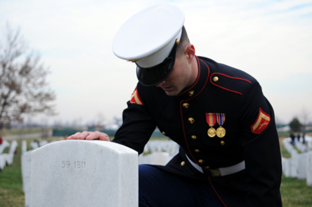 ARLINGTON NATIONAL CEMETERY, Va. – Lance Cpl. Adam Tucker, Combat Camera, Headquarters and Service Battalion, rests a hand upon a tombstone after placing a wreath upon it at Arlington National Cemetery on Dec. 15.