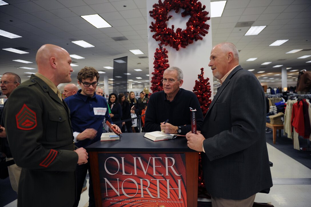 Retired Lt. Col. Oliver L. North, signs his new book “Heroes Proved” for Staff Sgt. Clinton Fowler, S-4 chief, Security Battalion and Steve Keene, retired master sergeant during his book signing at the Marine Corps Main Exchange on Thursday.  The lines were so long, North stayed an extra half hour to accommodate the masses.