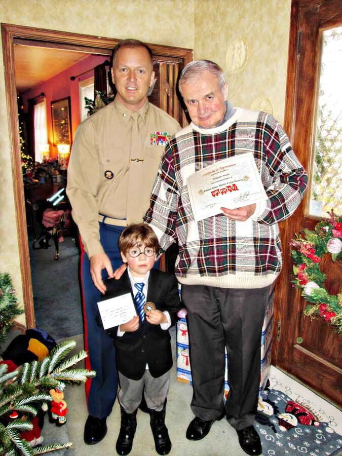 Marine Maj. Joe Skryd, a military deputy for supply chains solutions, NAVSUP Weapon Systems Support, presents Bill Nolan, a Defense Contracts Management Agency employee, and his grandson Tristan Nolan with tokens of appreciation from Navy Rear Adm. John G. King, the commander of NAVSUP WSS, and the Marine Corps in recognition of the six-year-old's generous donation of his birthday party gifts to the Toys for Tots Program. Toys were gathered up after Tristan's birthday party at his grandfather's house, Dec. 8, in Berwyn, Pa. (Photo by Margaret Kenyon-Ely, NAVSUP WSS Corporate Communications/Released)